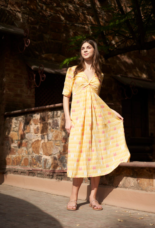 Woman in a yellow dress standing in front of a stone wall.