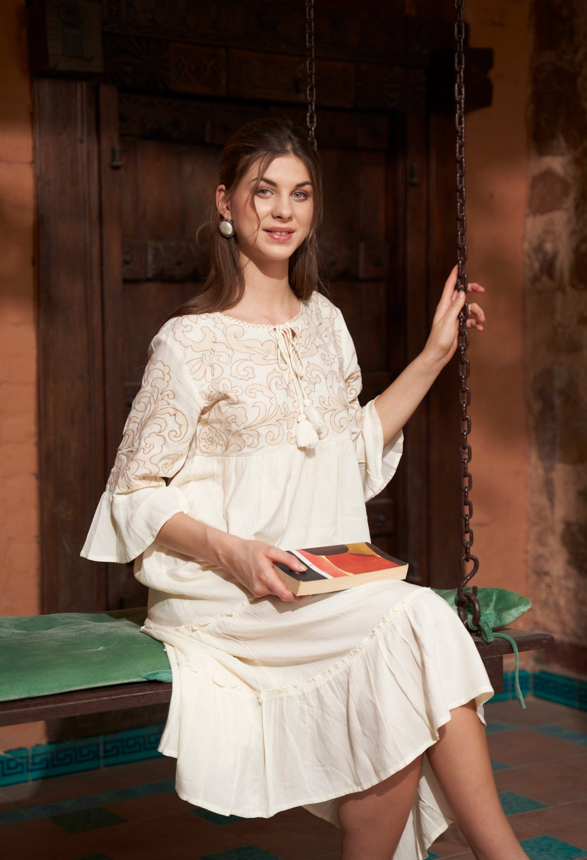 Woman in a ivory dress holding a book in a rustic setting