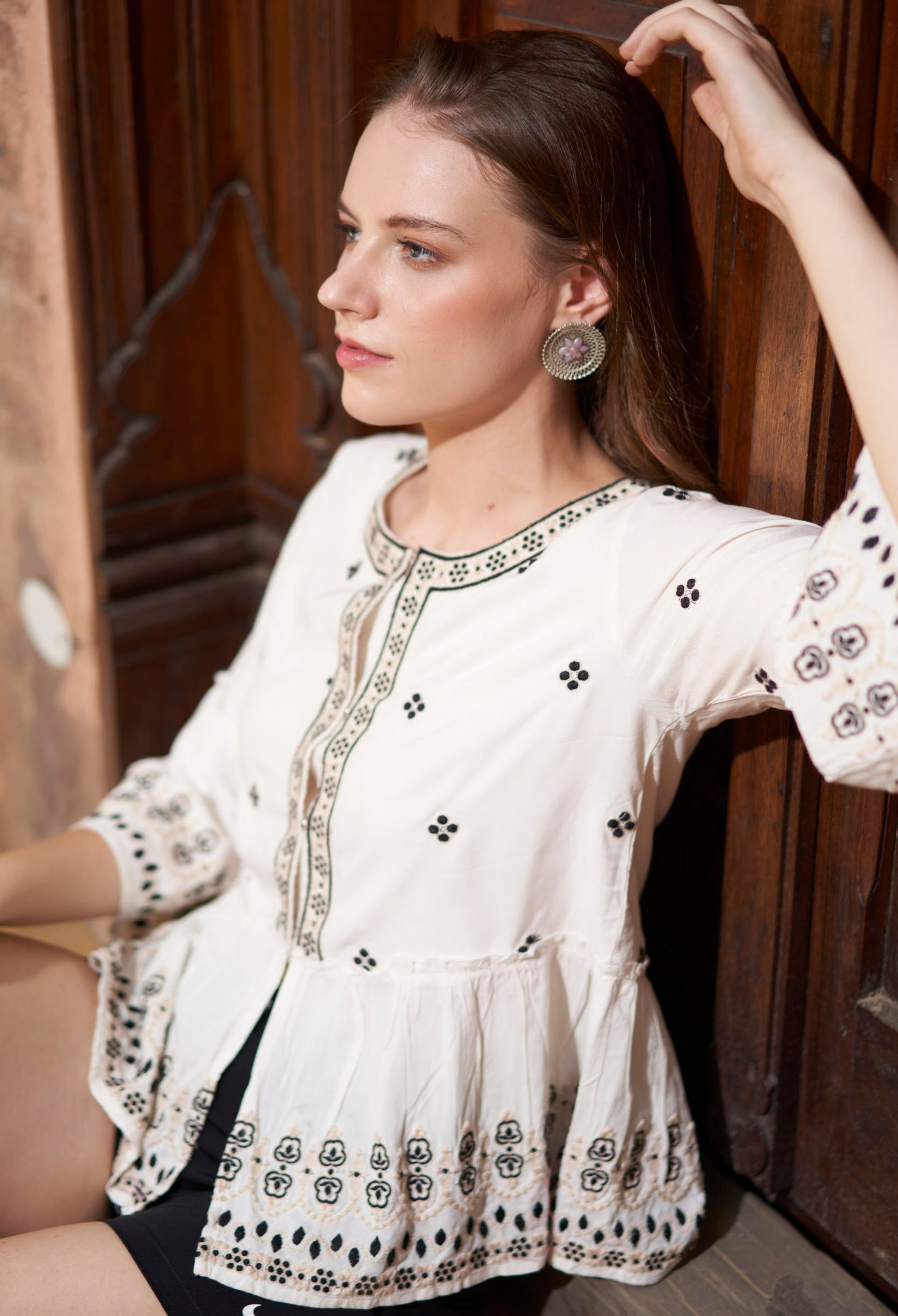 Woman wearing a white blouse with black patterns in an indoor setting