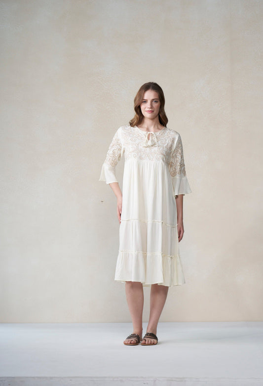 Woman wearing a ivory lace dress against a plain background