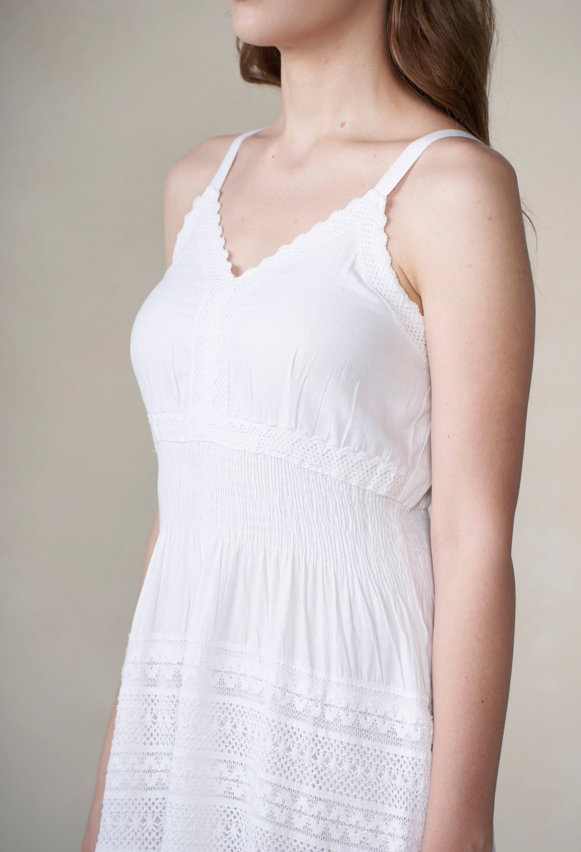 White sleeveless dress with lace details on a neutral background