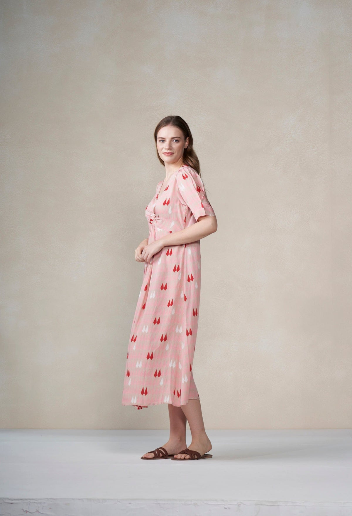 Woman wearing a pink dress with a pattern against a plain background