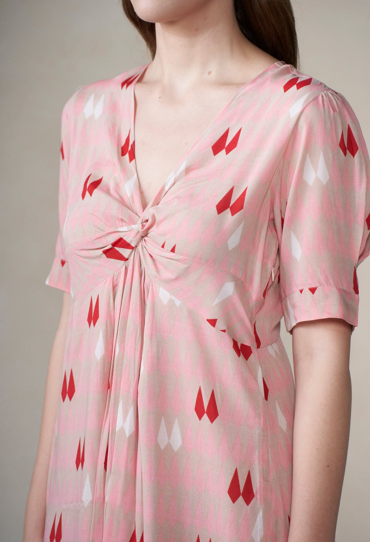 Pink dress with red pattern worn by a person against a neutral background