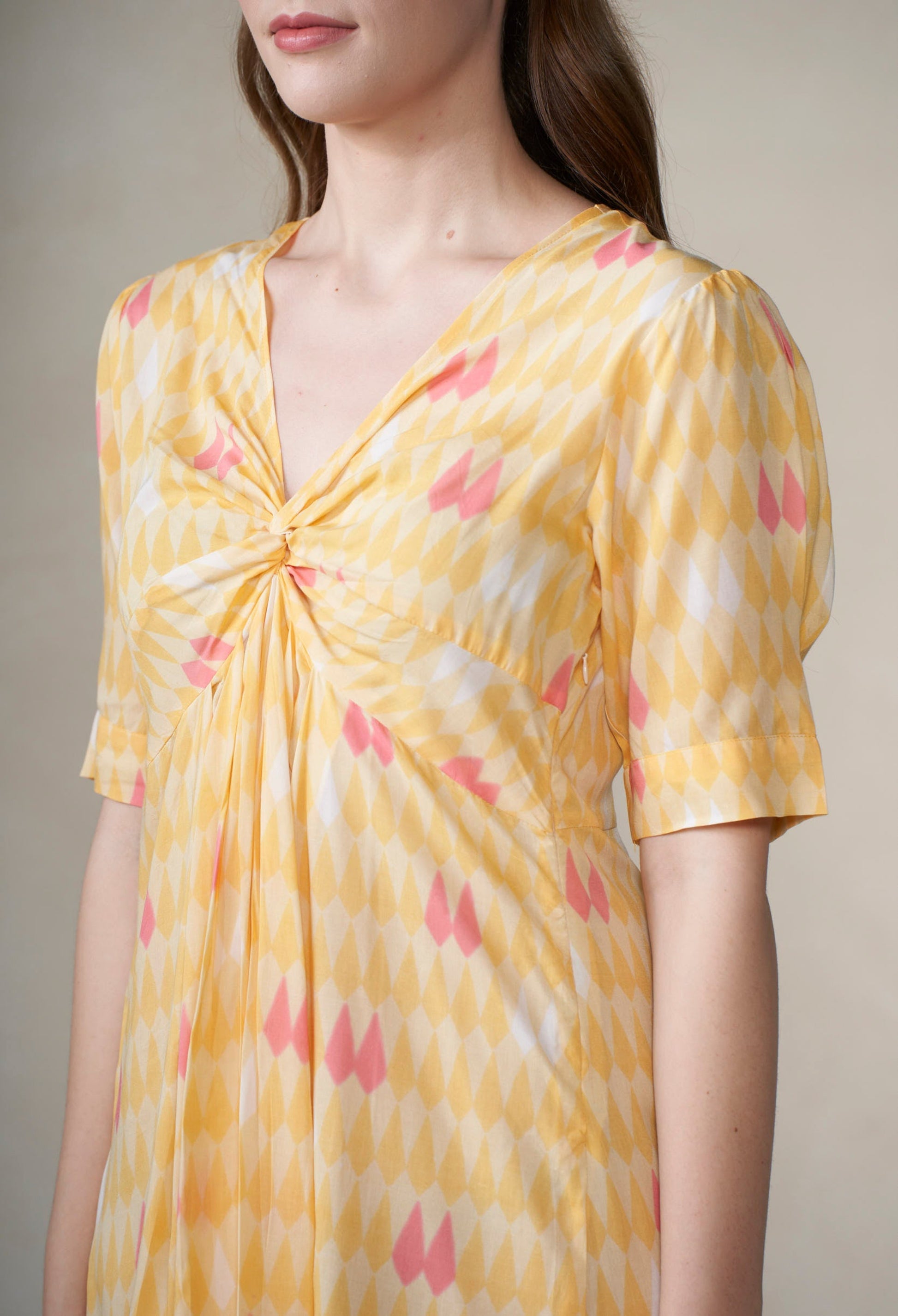 Yellow dress with pink floral pattern worn by a person against a neutral background