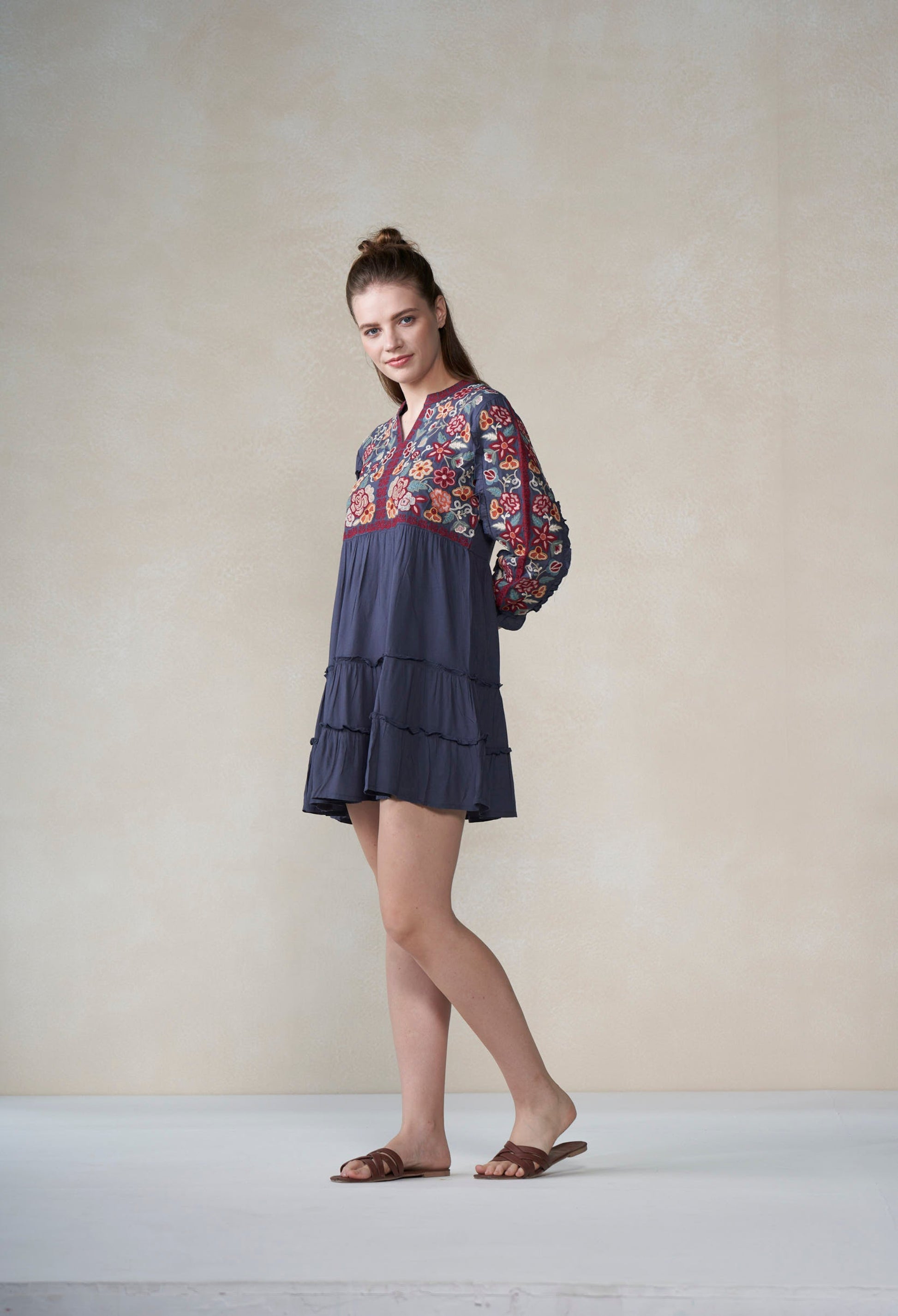 Woman wearing a blue dress with floral patterns on a plain background