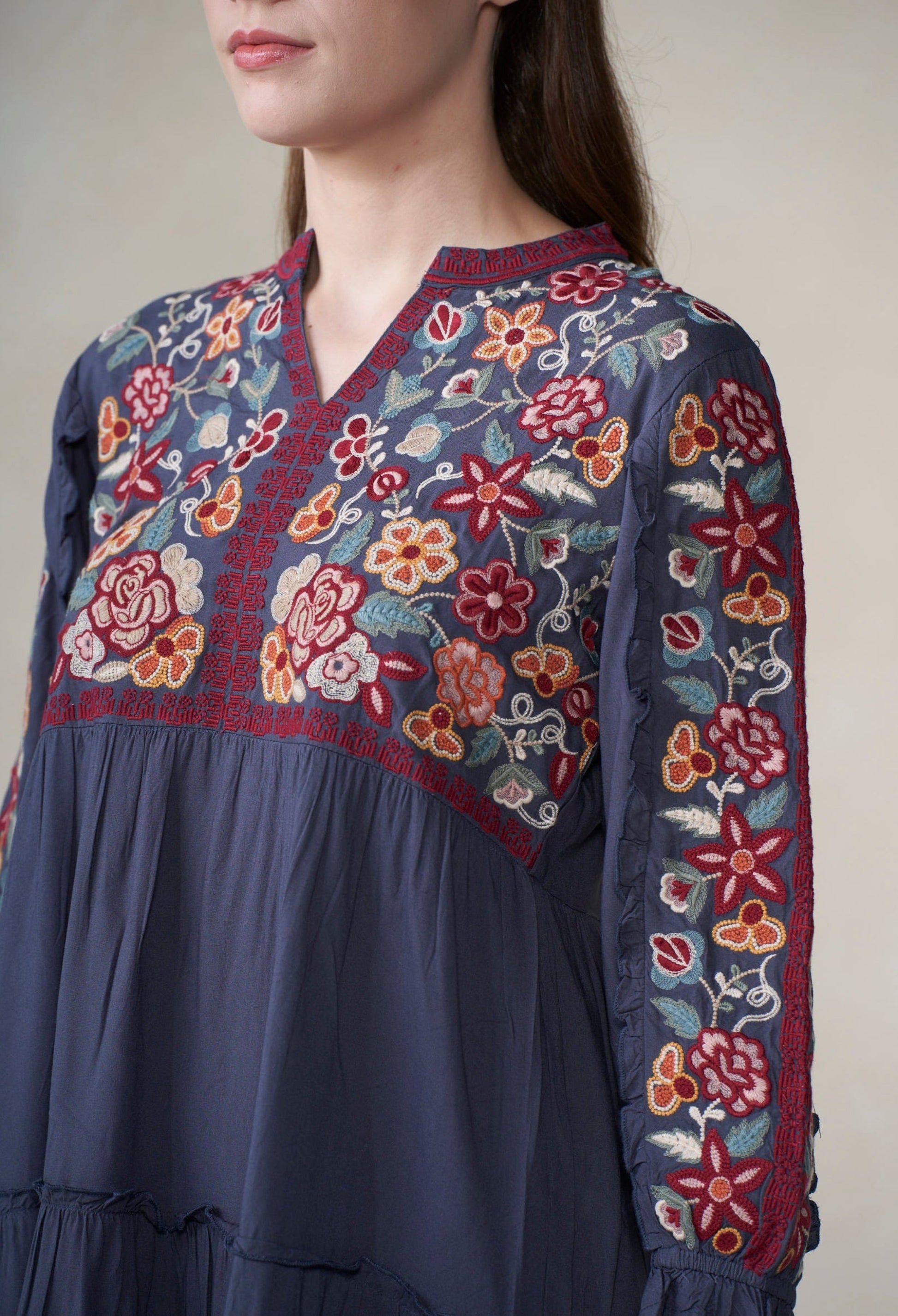 Navy blue dress with colorful floral embroidery on a plain background