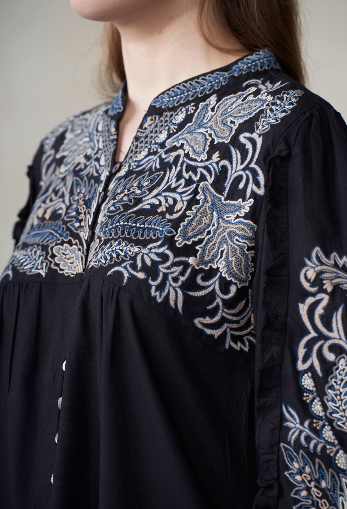 Black dress with intricate white embroidery on a neutral background