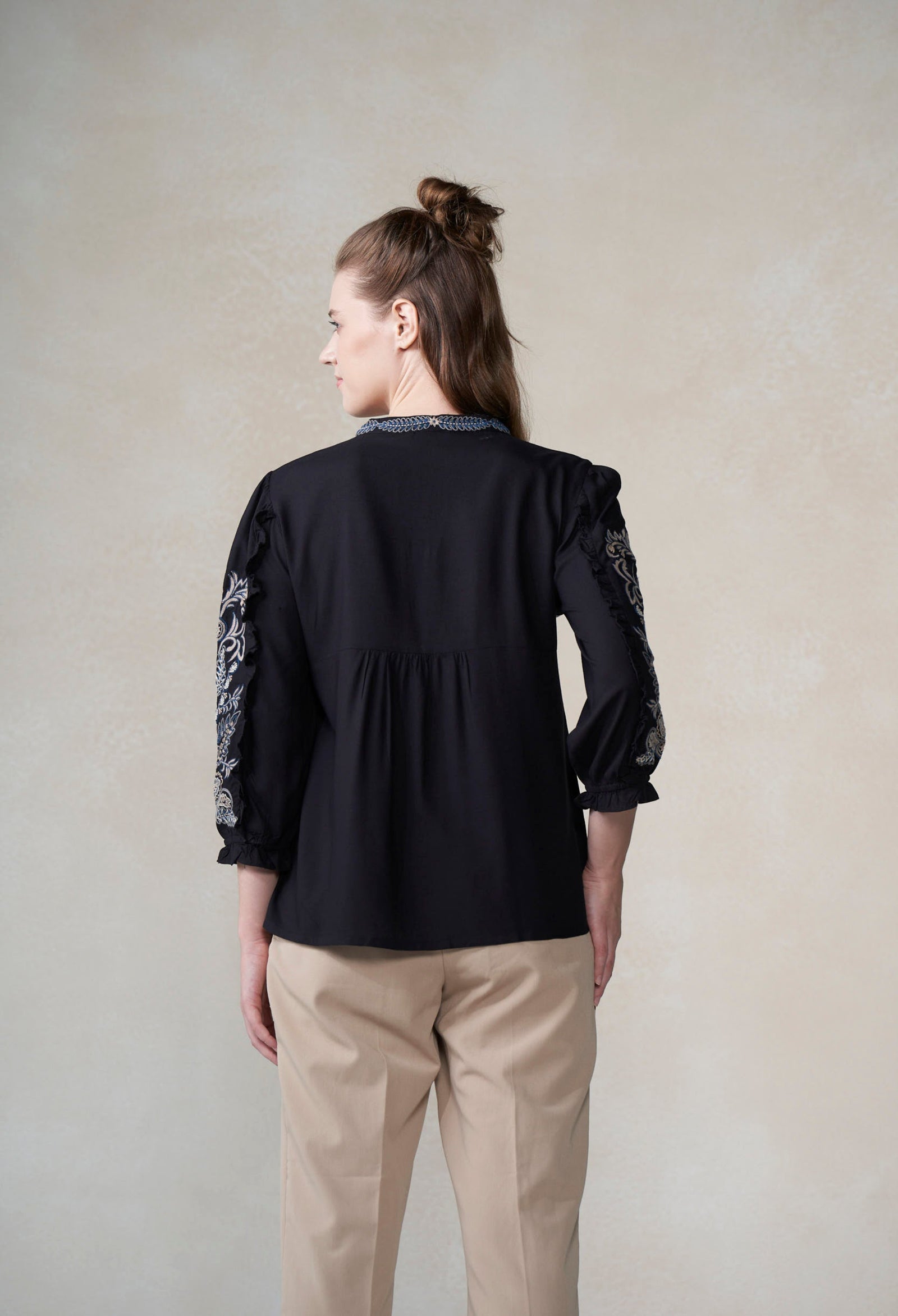 Woman wearing a black blouse with lace sleeves against a plain background