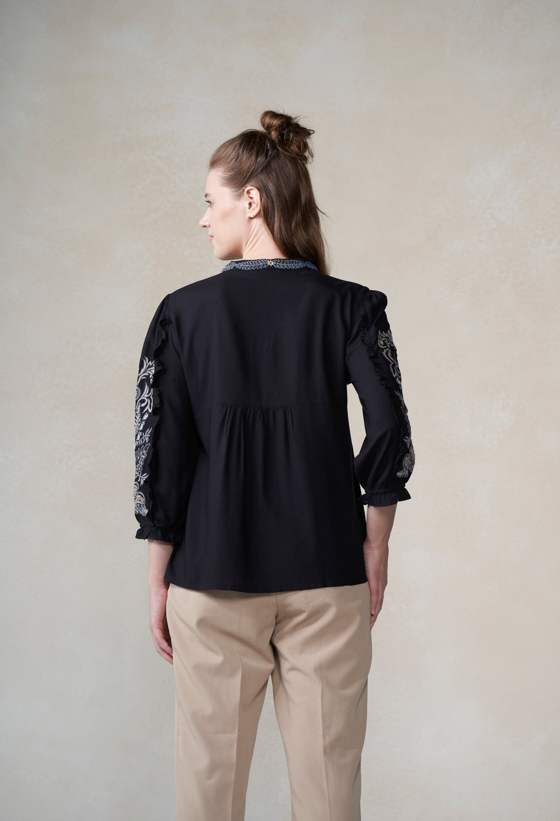 Woman wearing a black blouse with lace sleeves against a plain background