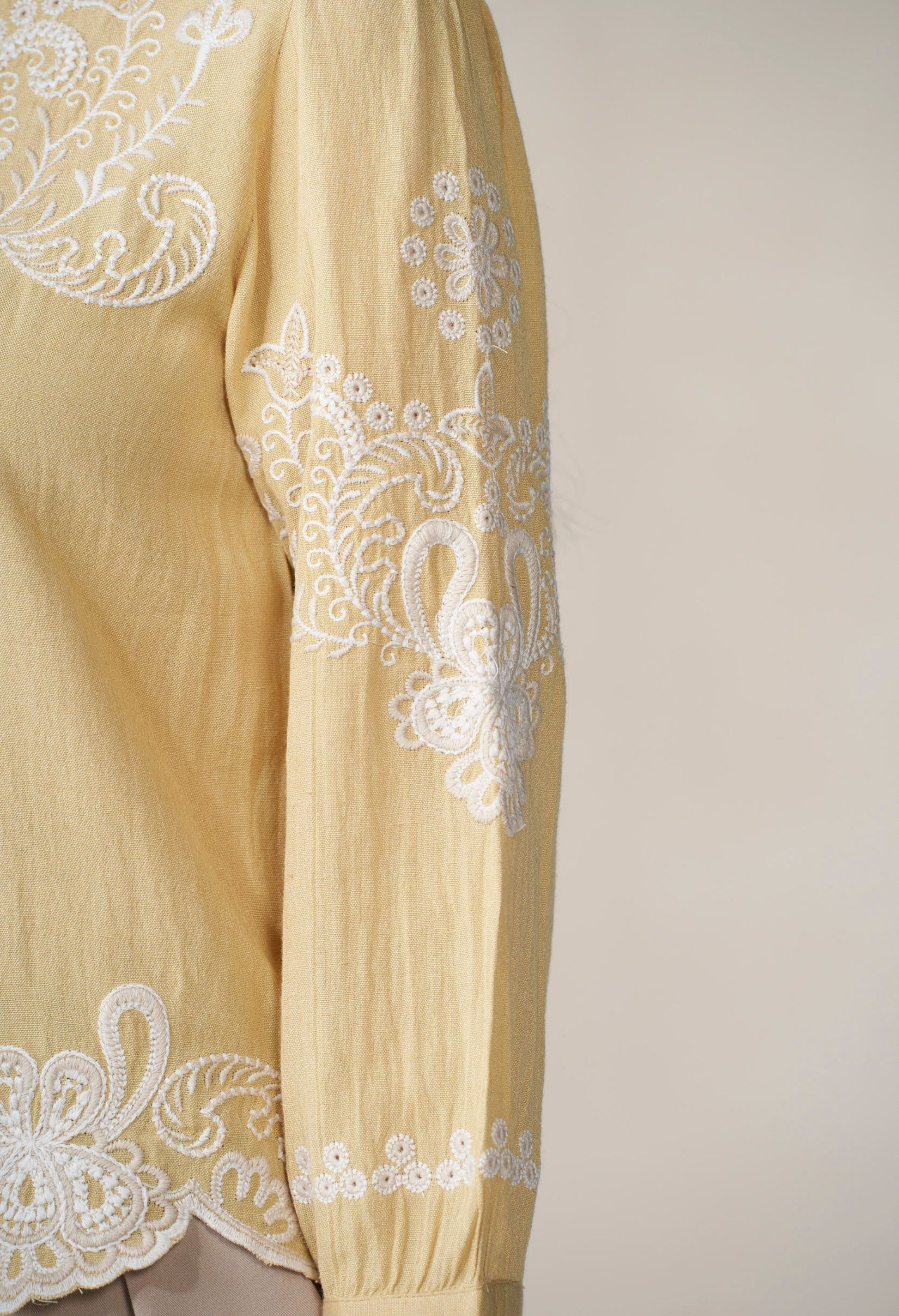 Light yellow fabric with white lace embroidery on a plain background
