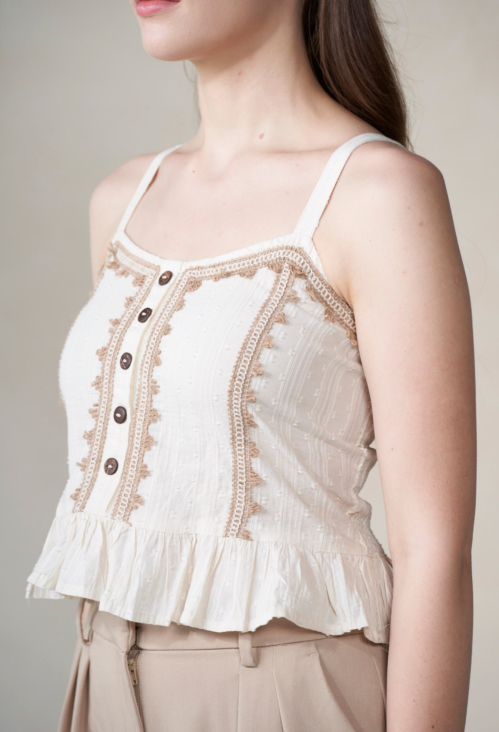 White lace-trimmed top worn by a person on a neutral background