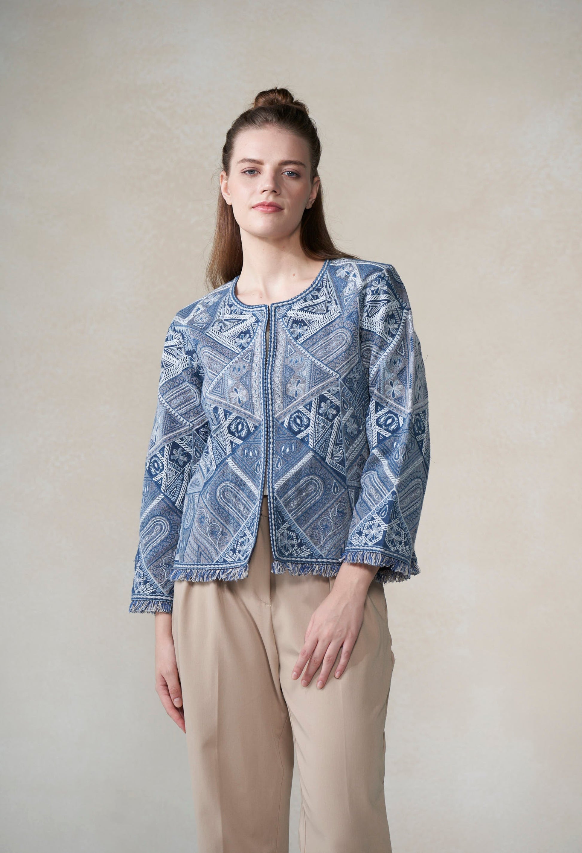 Woman wearing a blue patterned jacket against a plain background