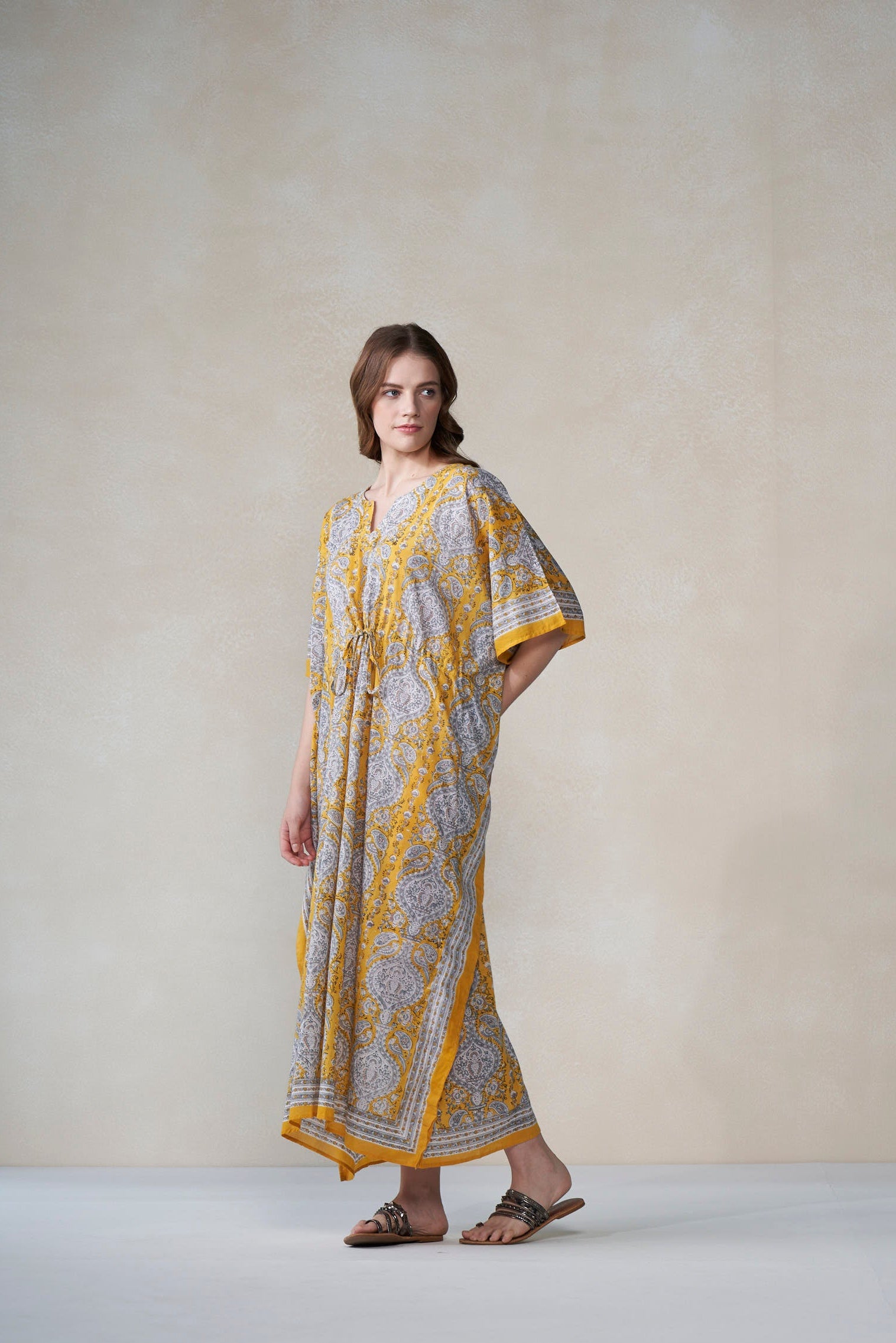 Woman wearing a patterned dress with yellow accents against a plain background