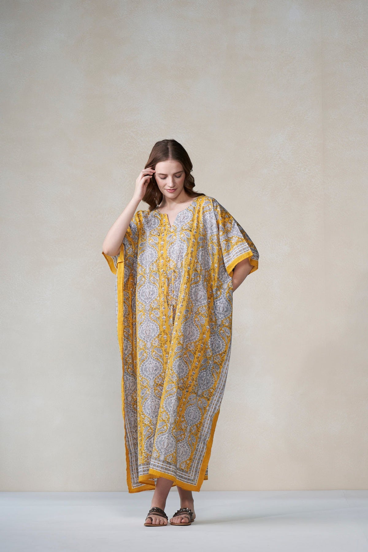 Woman wearing a patterned dress with yellow accents against a plain background