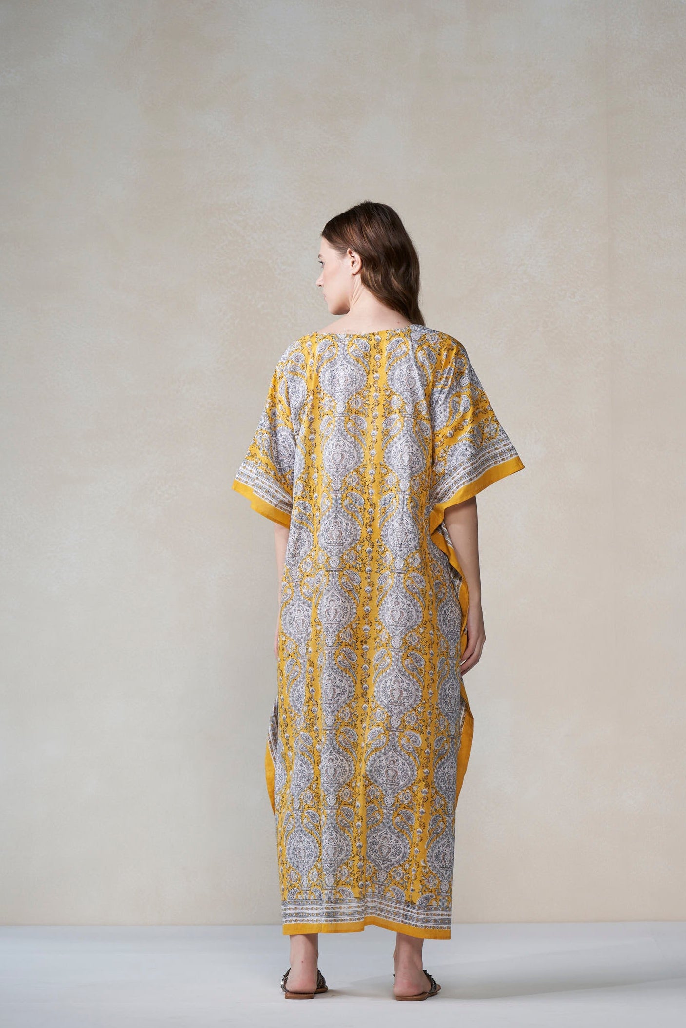 Woman wearing a yellow and gray patterned dress against a plain background