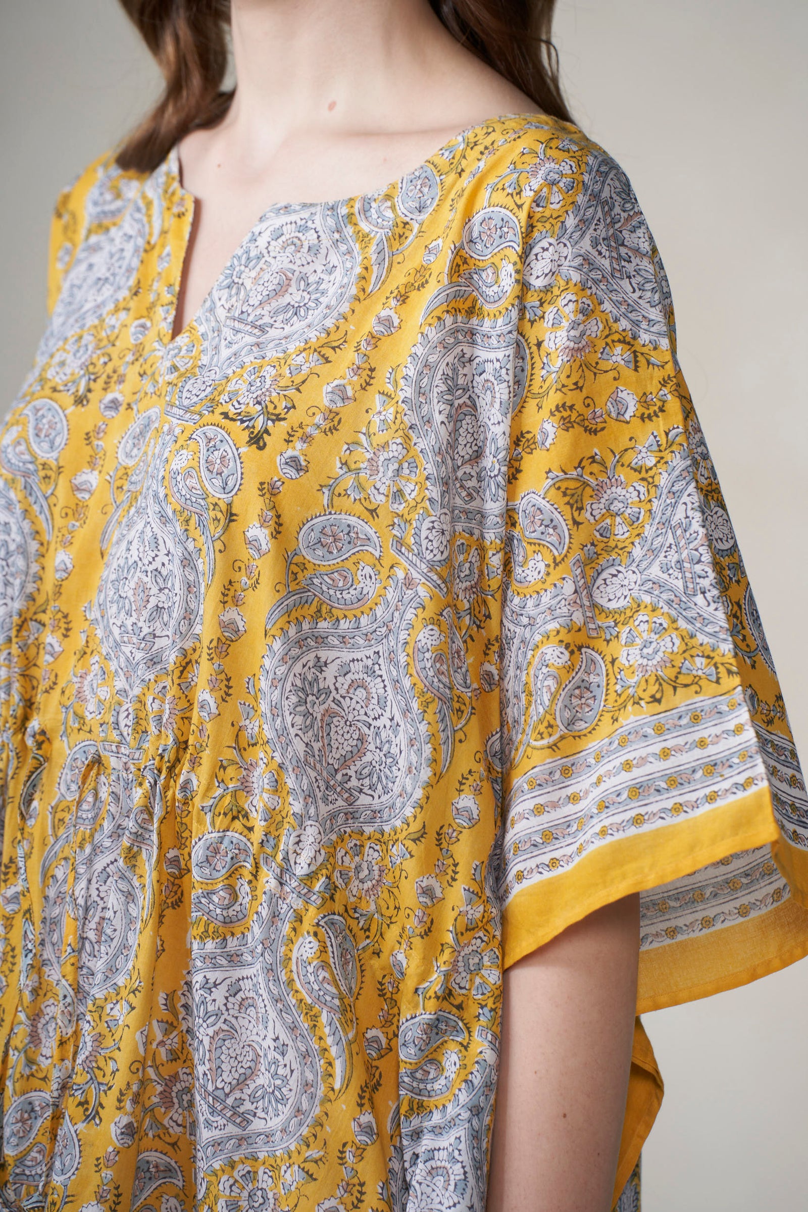 Yellow and gray patterned fabric draped over a person against a neutral background