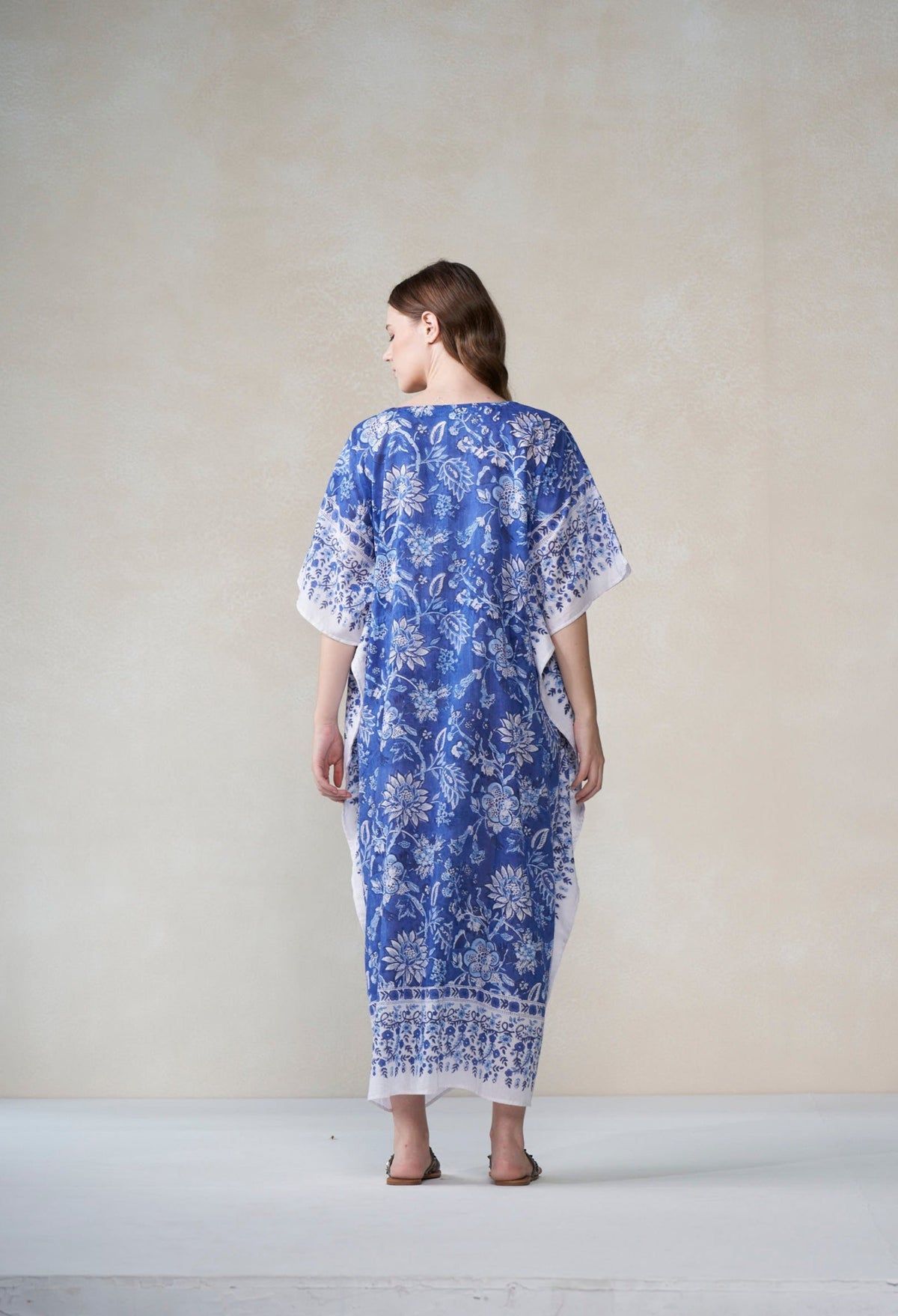 Woman wearing a blue and white patterned dress against a plain background