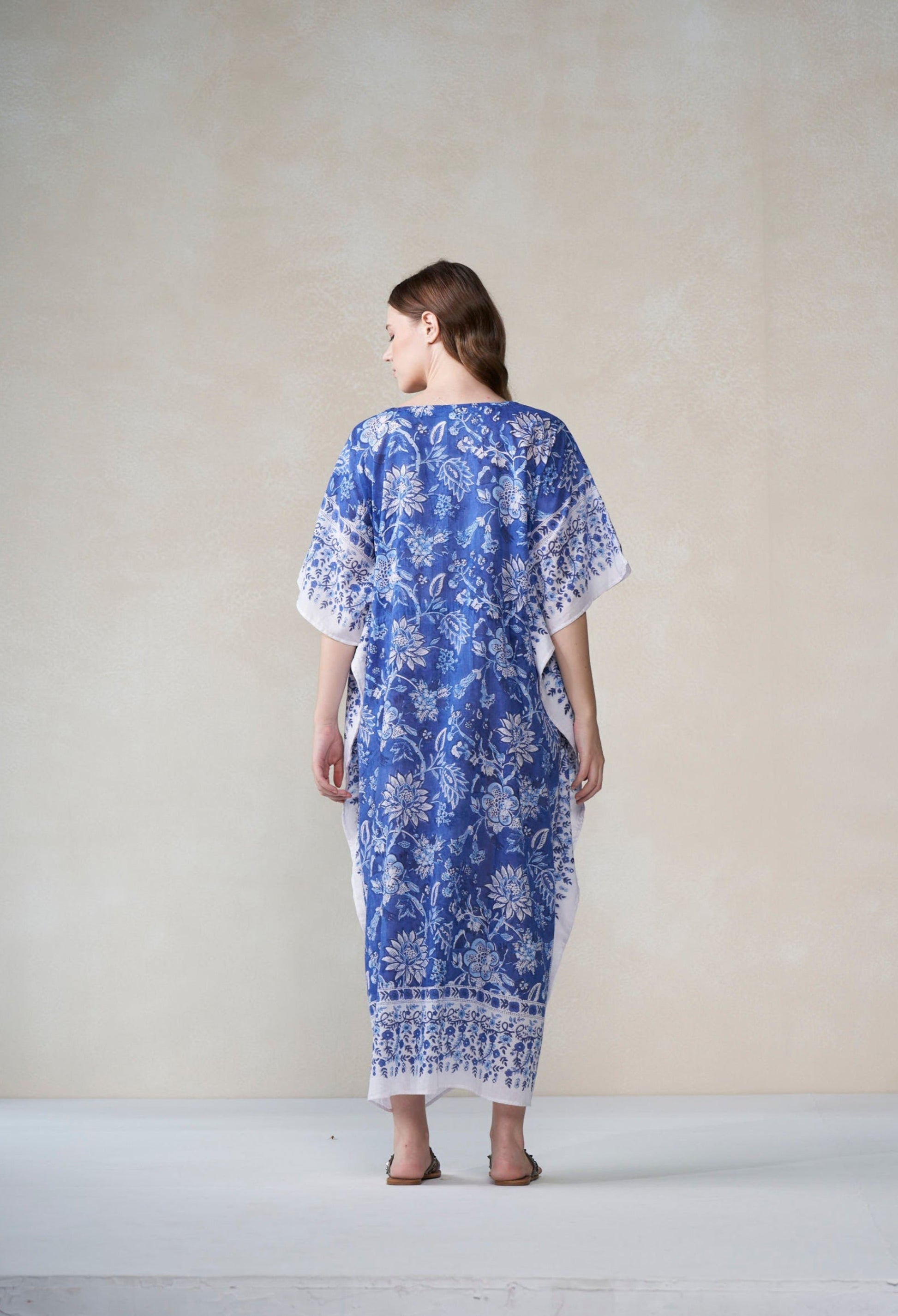 Woman wearing a blue and white patterned dress against a plain background