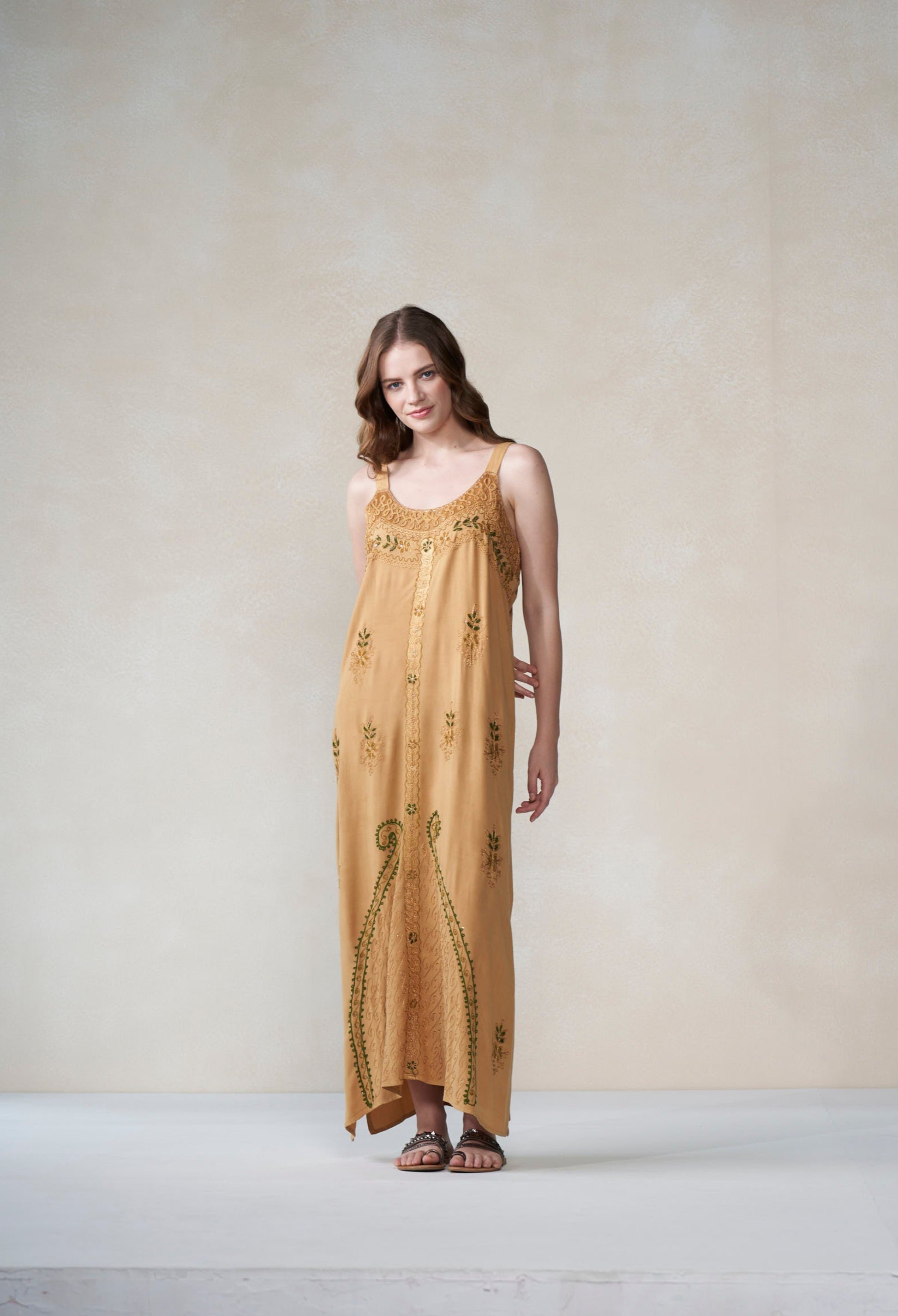 Woman wearing a long, patterned dress against a plain background