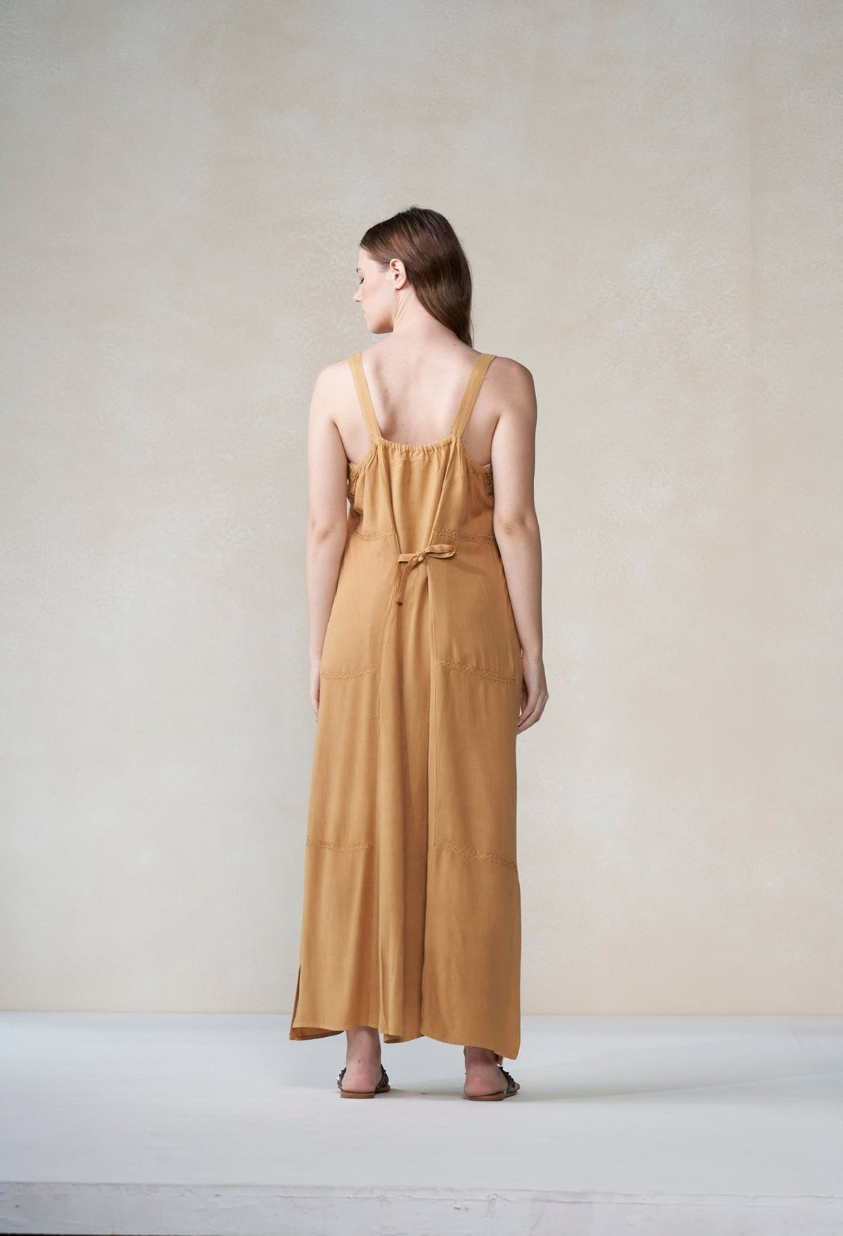 Woman wearing a mustard yellow dress against a plain background