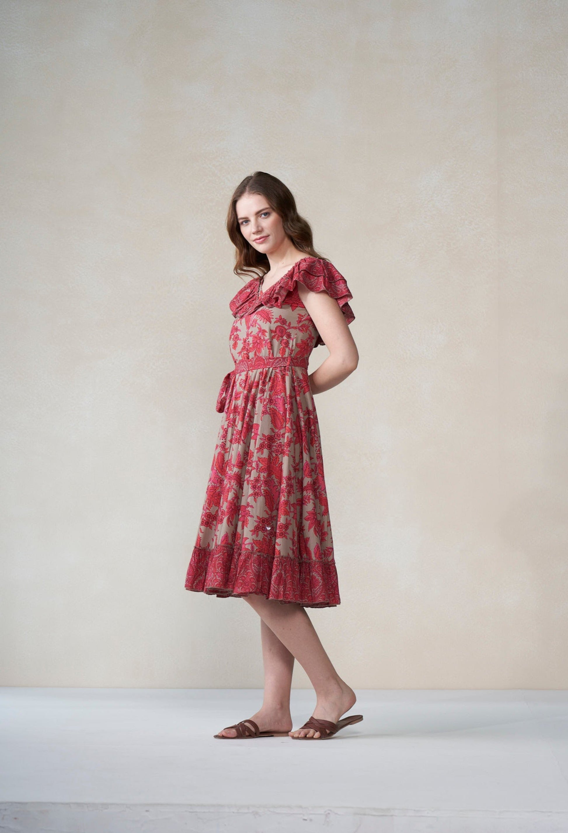 Woman wearing a red floral dress against a plain background