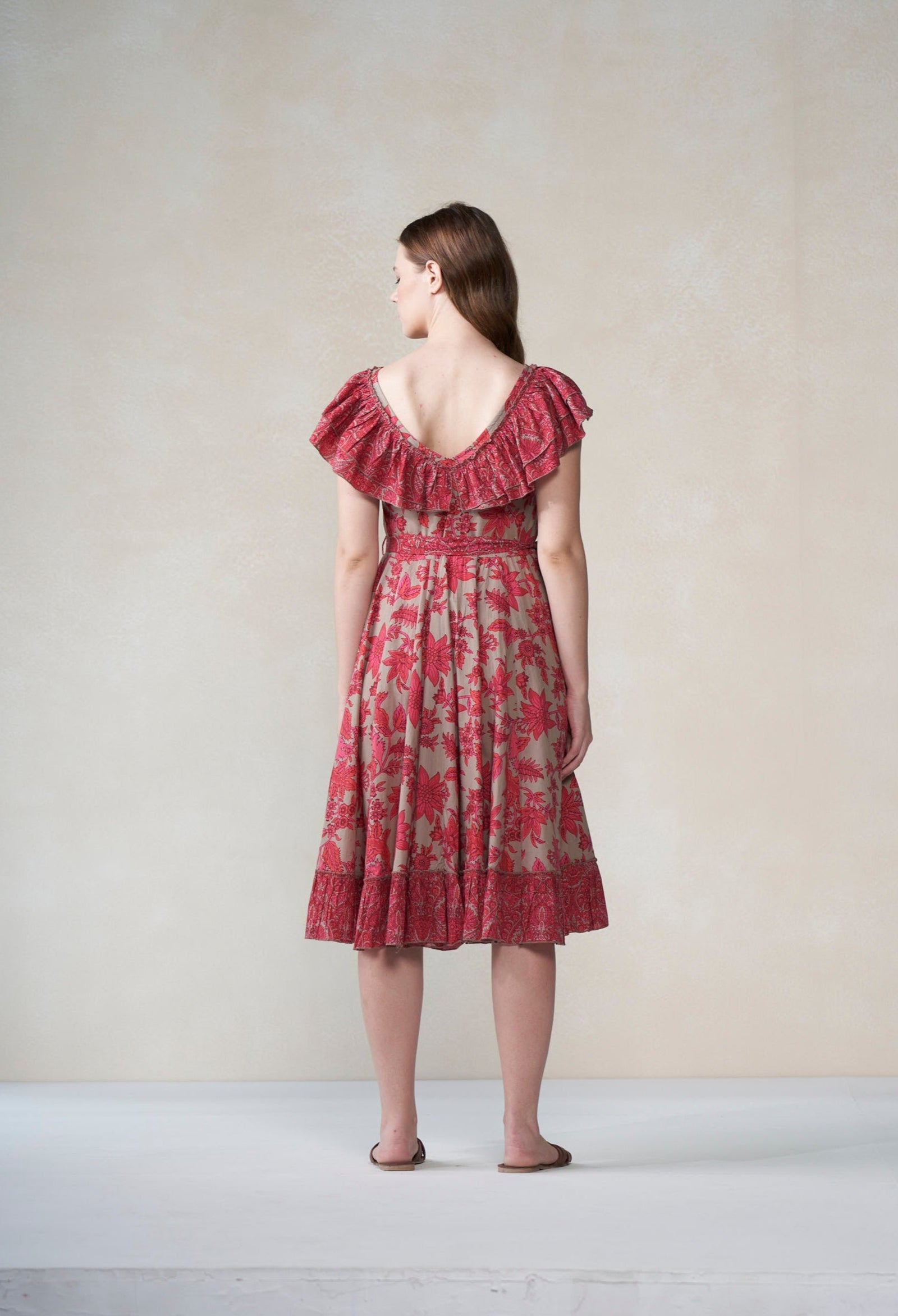 Woman wearing a red floral dress against a plain background