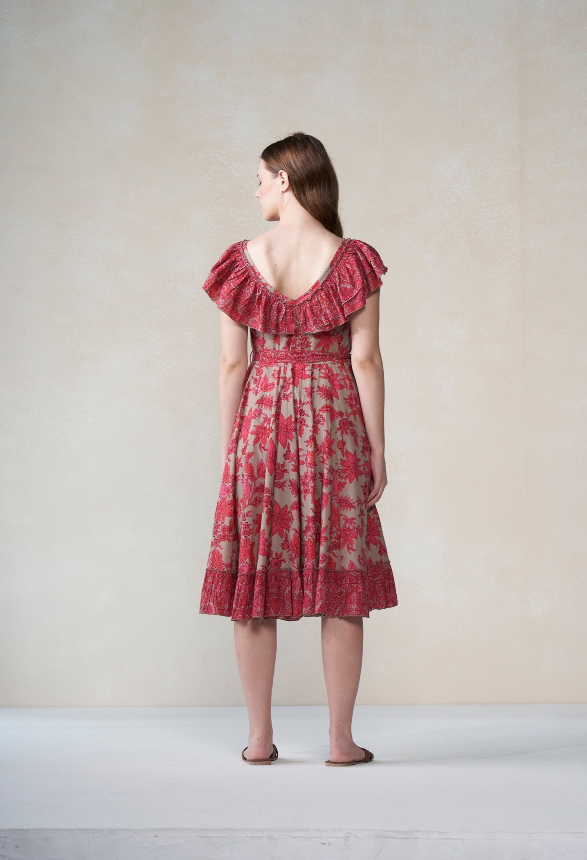 Woman wearing a red floral dress against a plain background