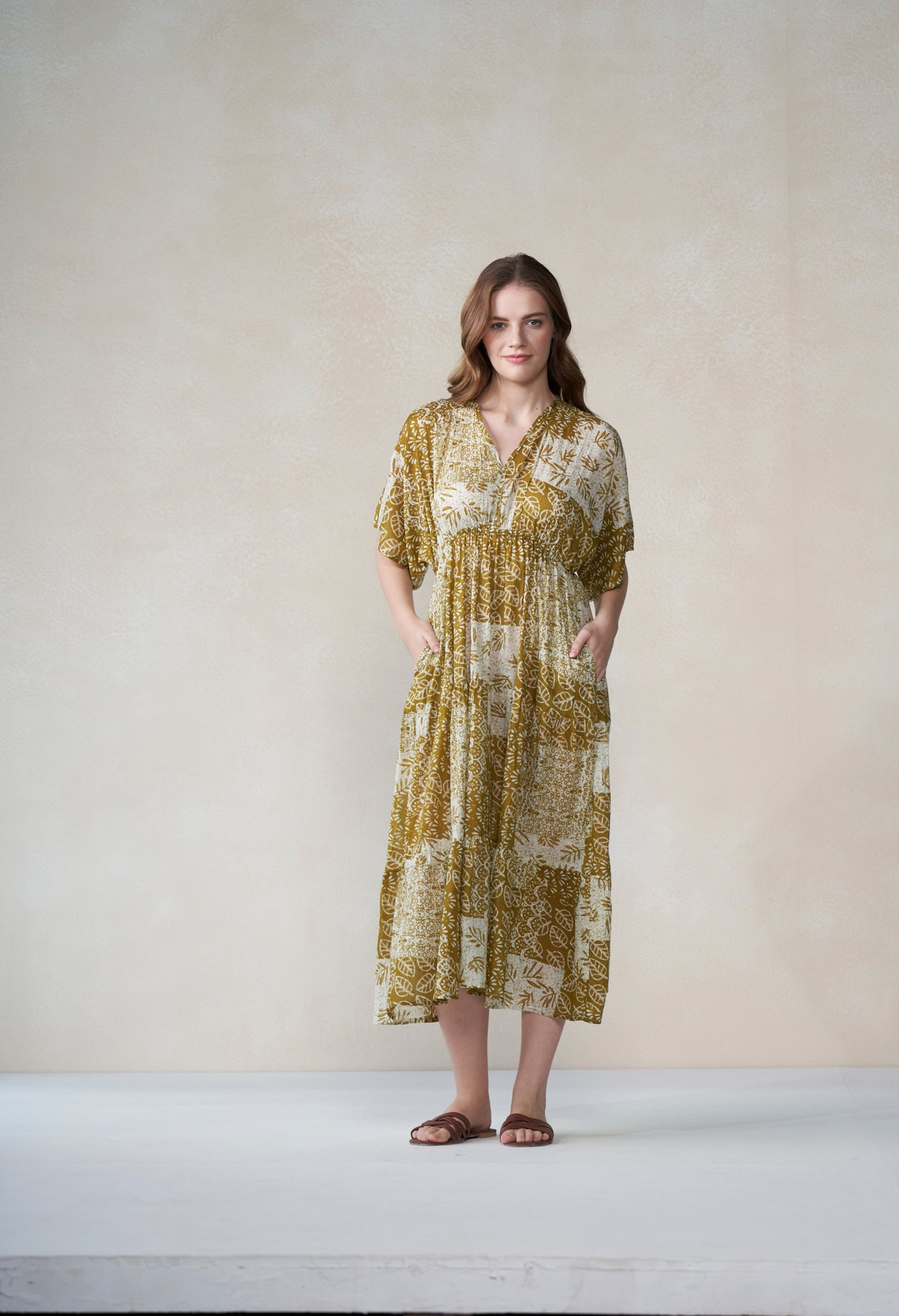 Woman wearing a patterned dress standing against a plain background