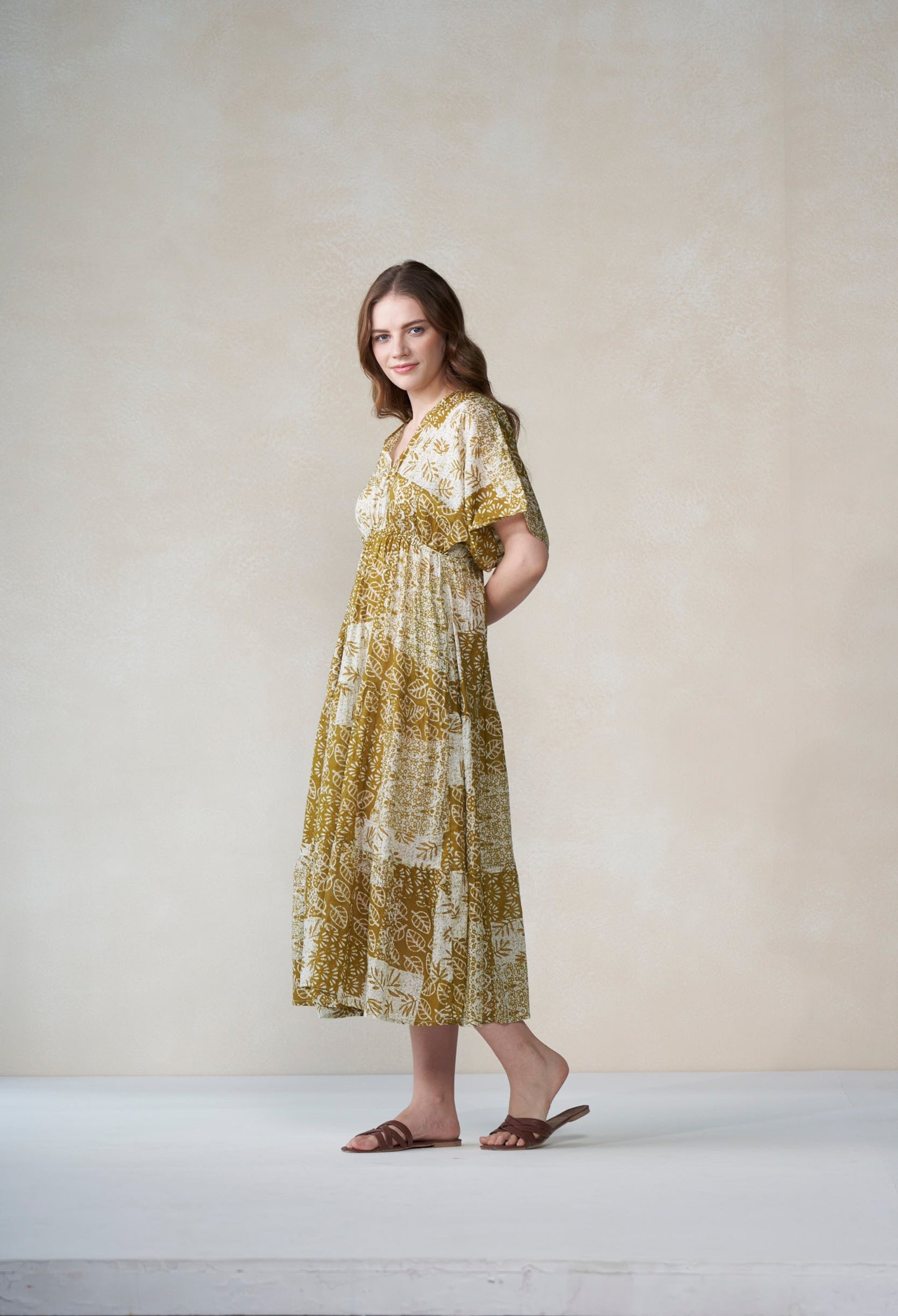 Woman wearing a patterned dress standing against a plain background