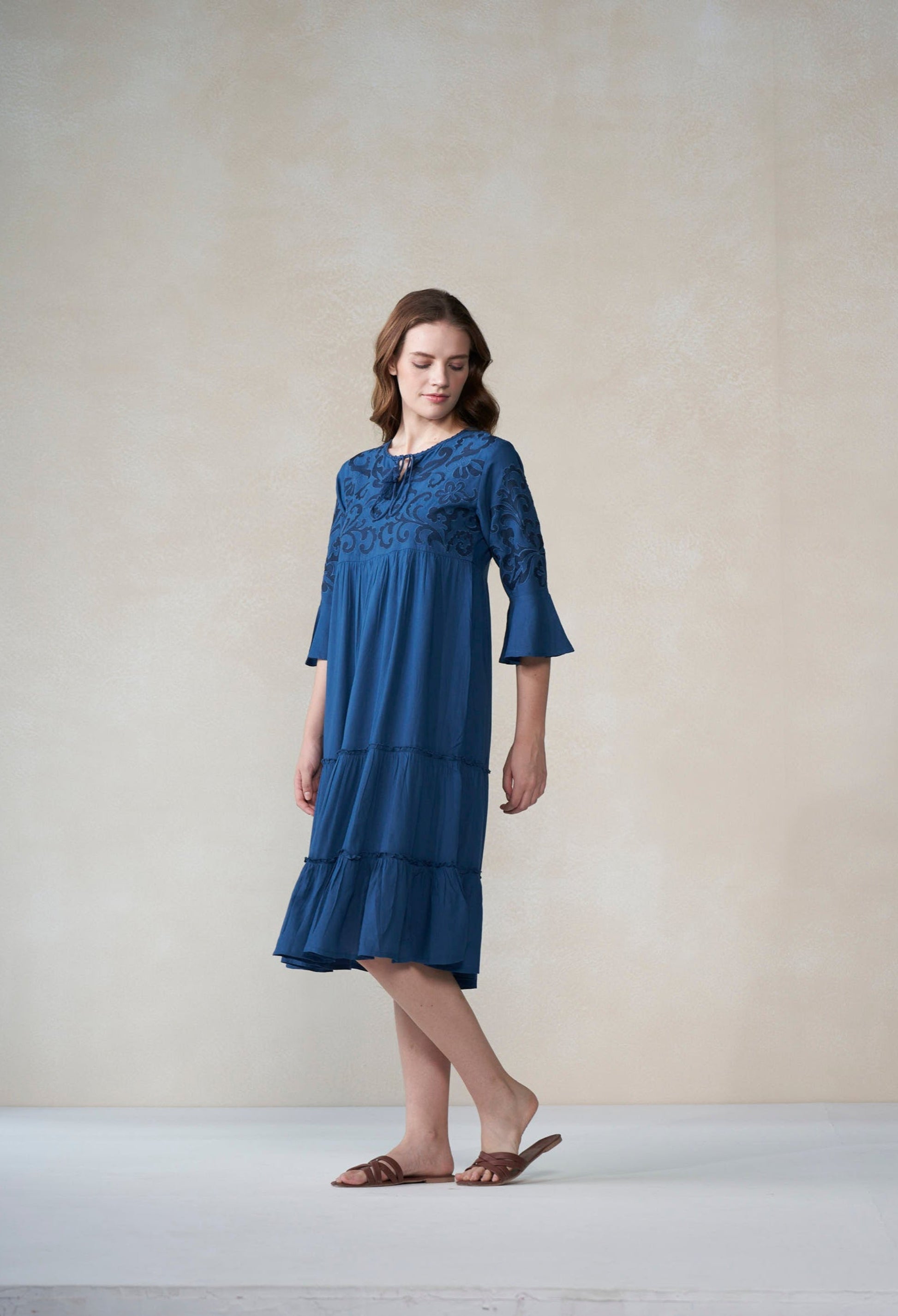 Woman wearing a blue dress standing against a plain background
