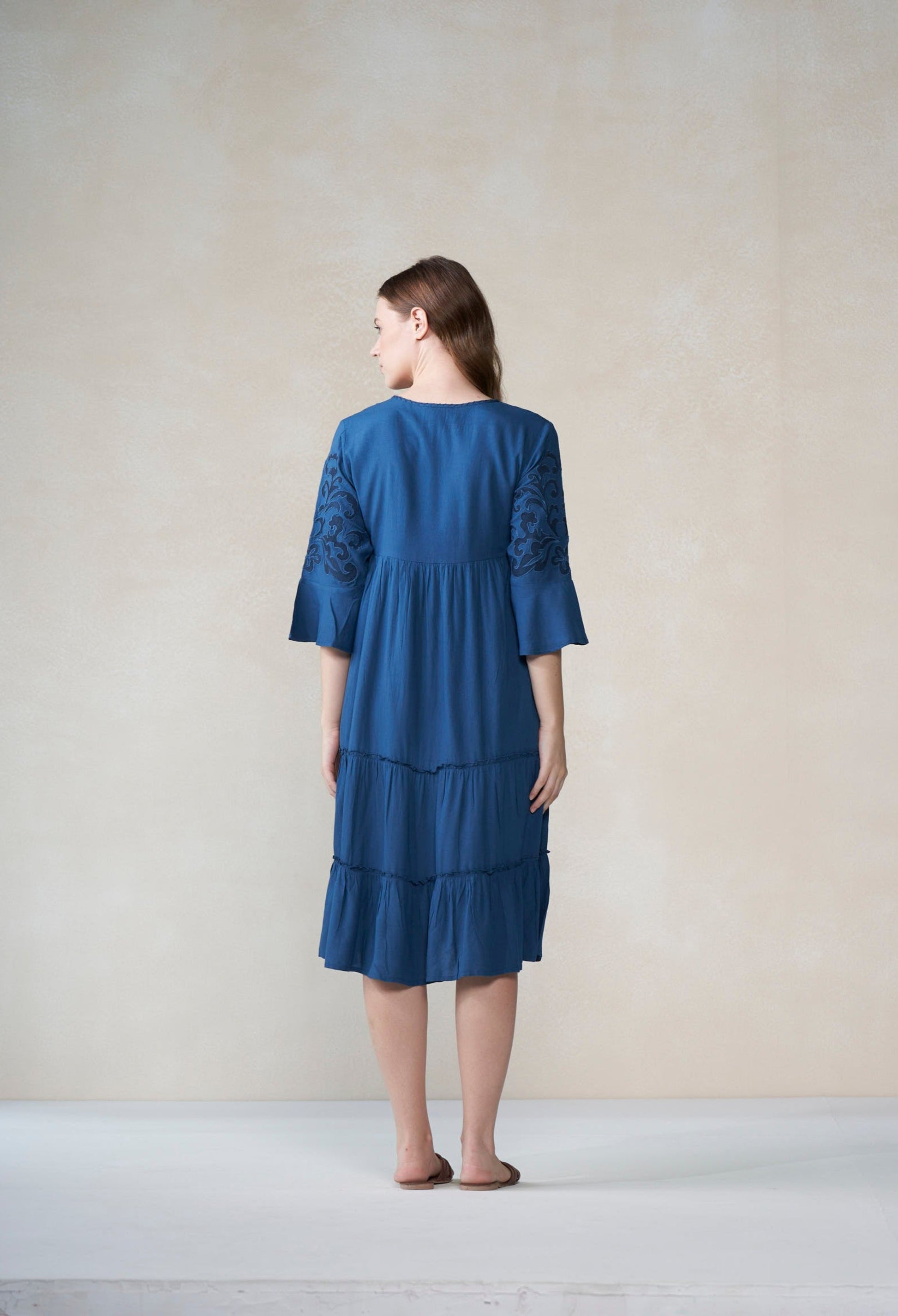 Woman wearing a blue dress standing against a plain background