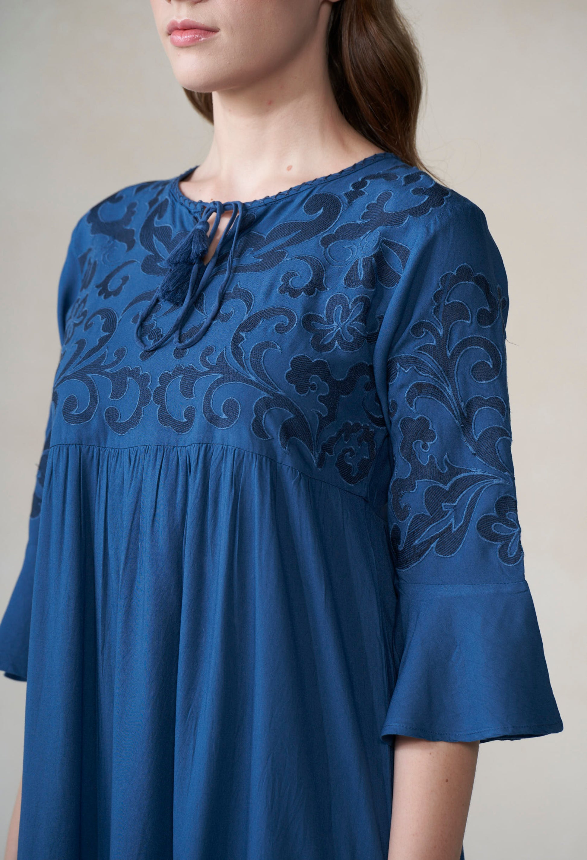 Blue dress with intricate black lace detailing on a plain background