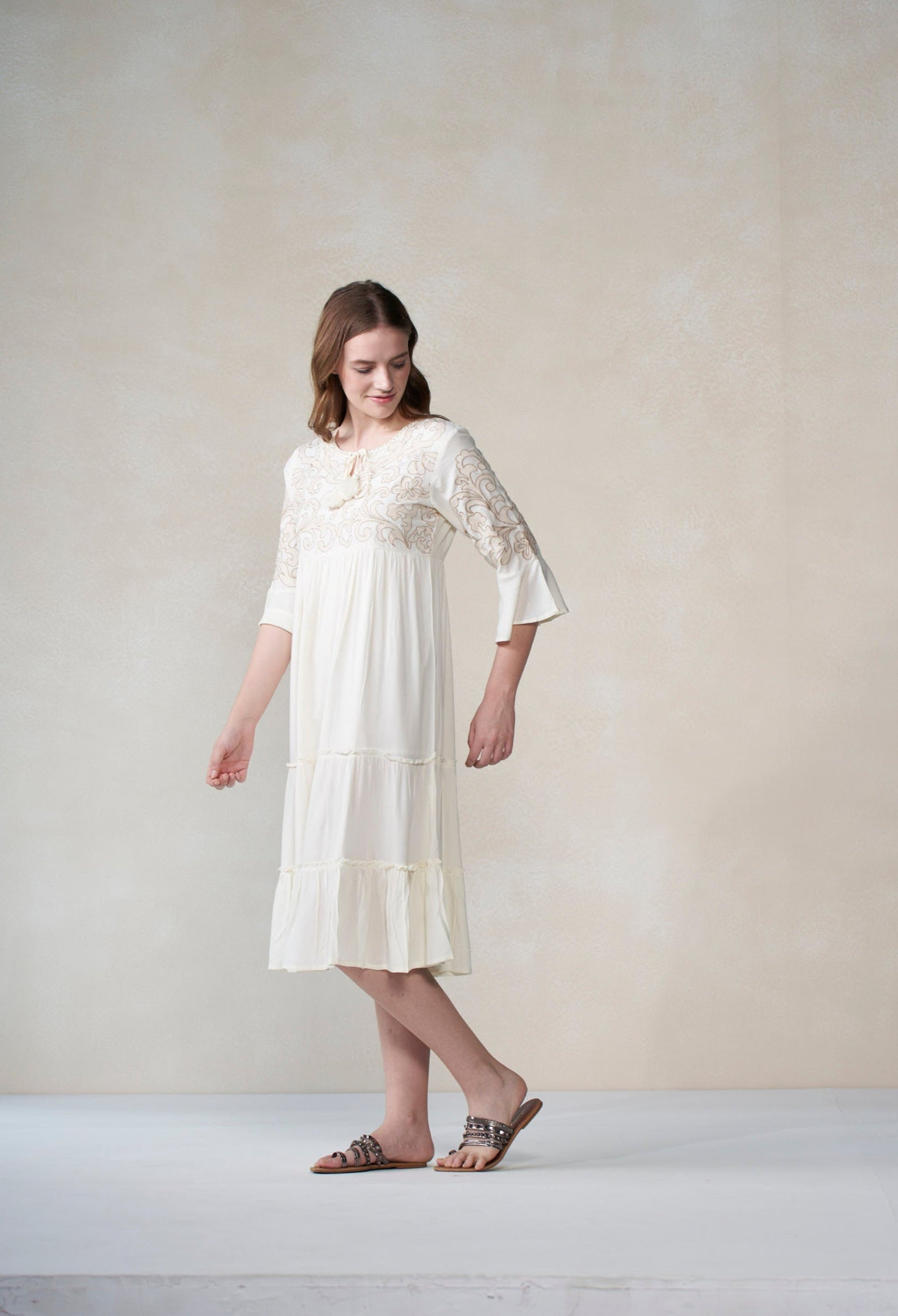 Woman wearing a white lace dress against a plain background