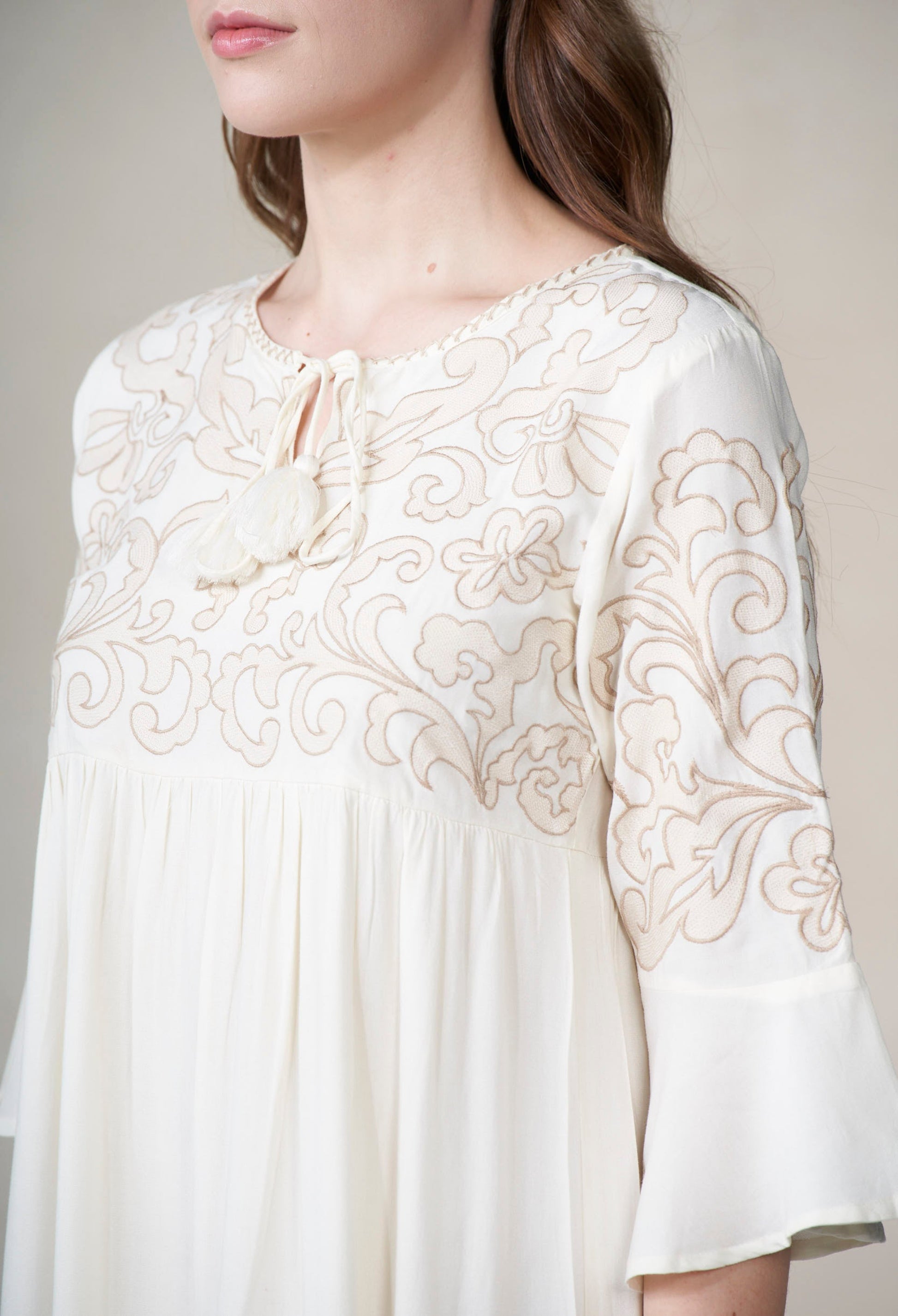 ivory blouse with intricate gold embroidery on a plain background
