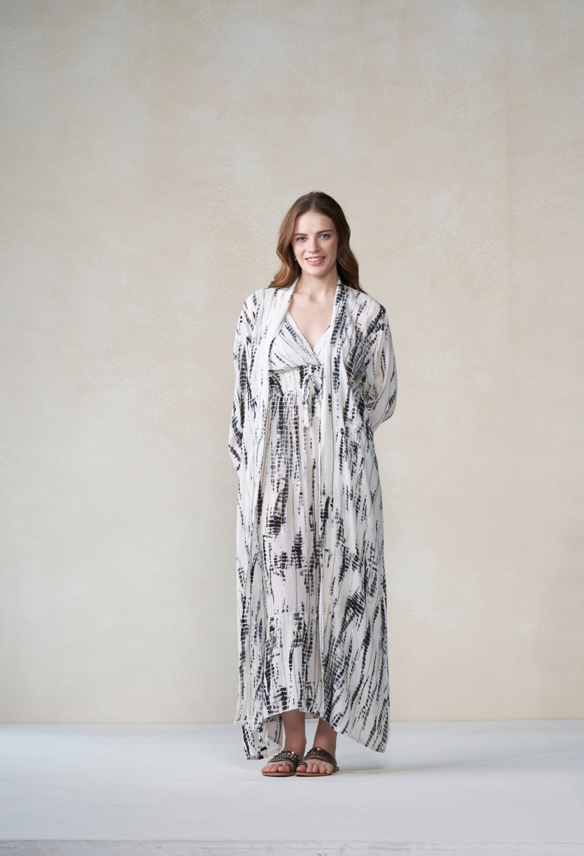 Woman wearing a long, patterned dress against a plain background