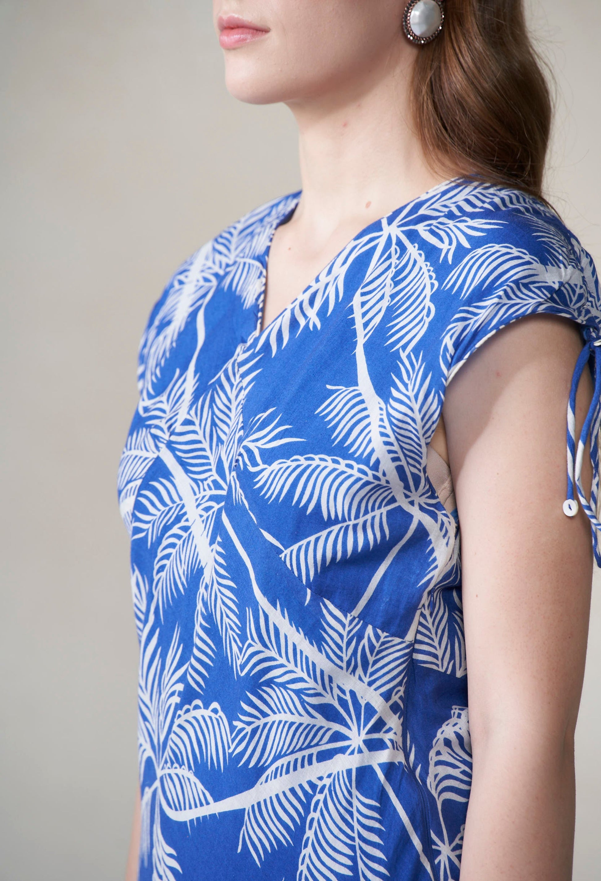 Blue top with white leaf pattern worn by a person against a neutral background