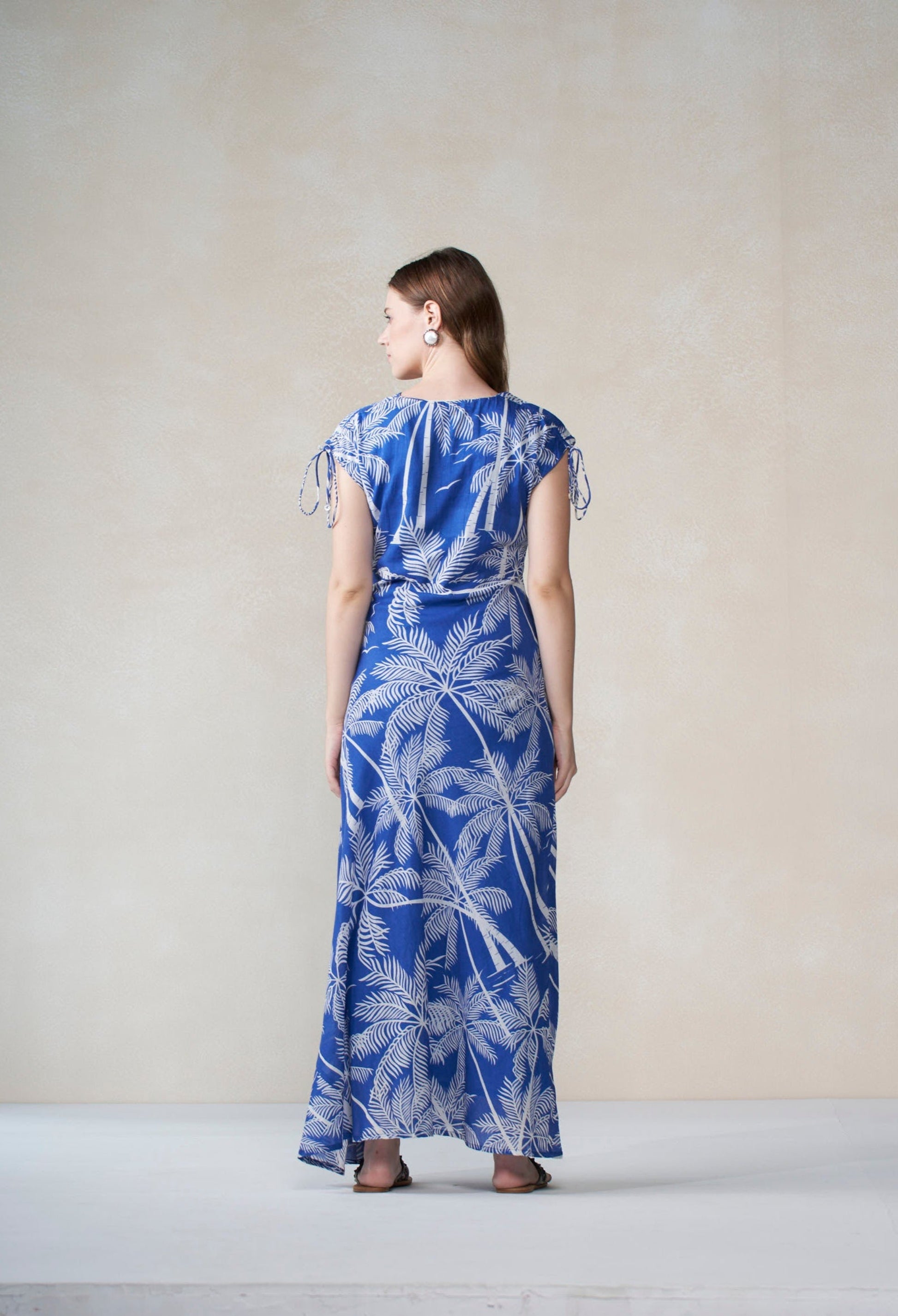 Woman wearing a blue and white floral dress against a plain background