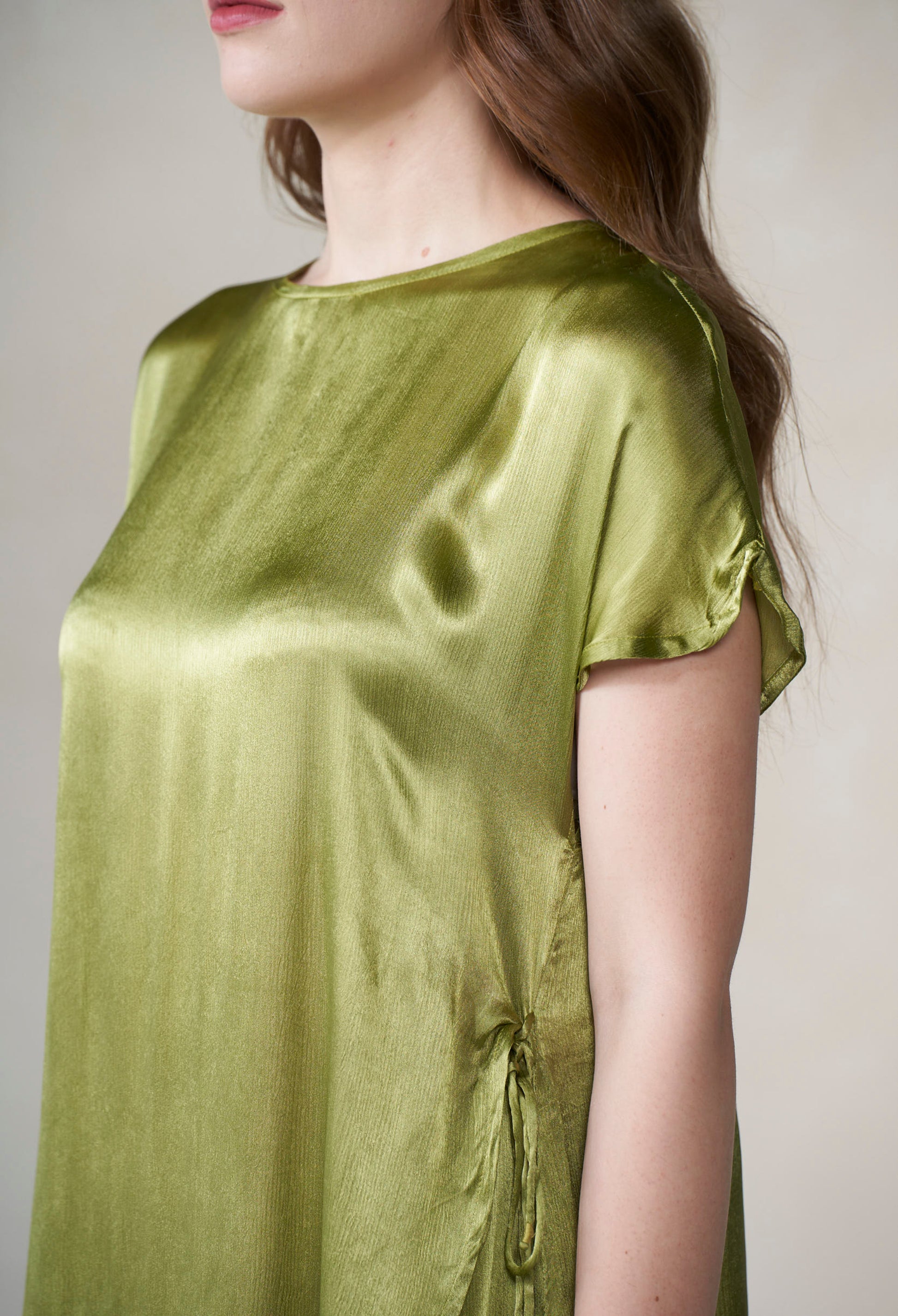 Woman wearing a green satin dress against a neutral background