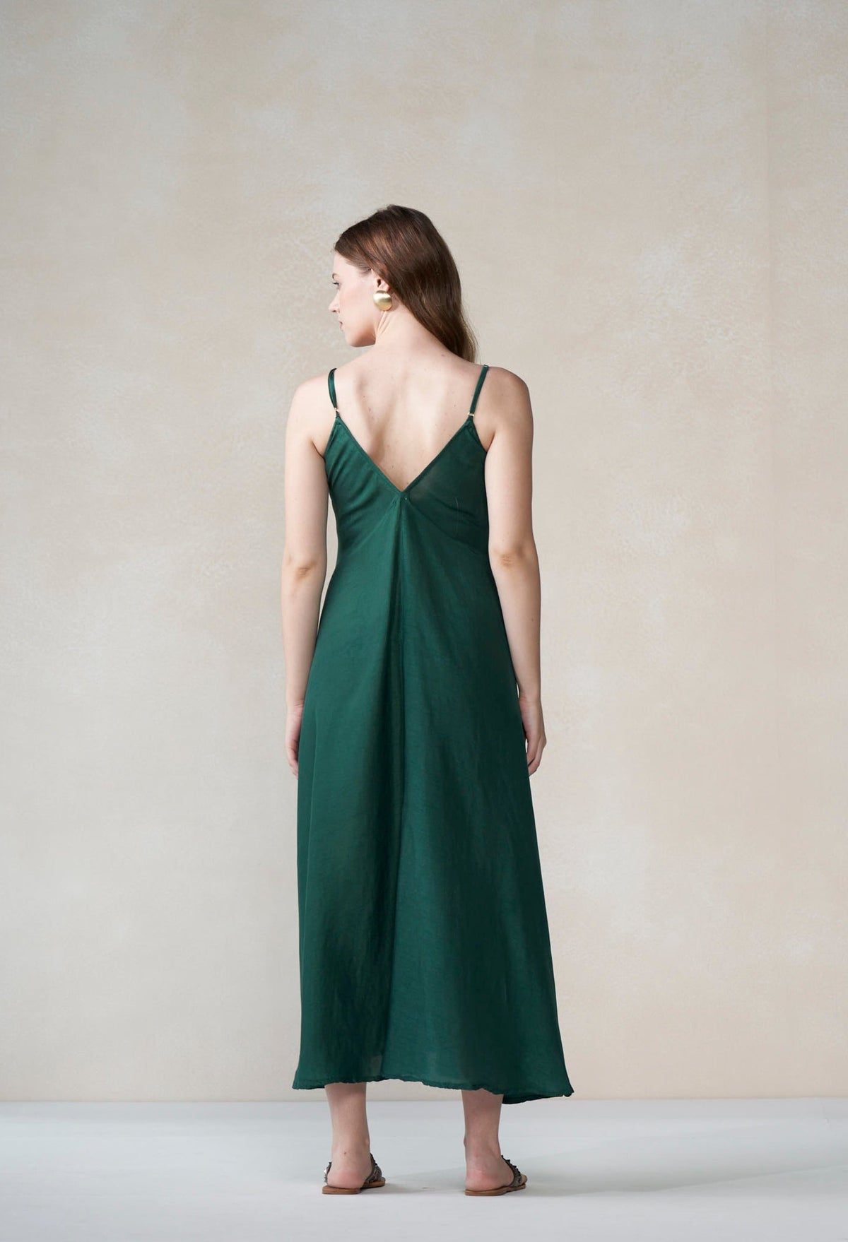 Woman wearing a green slip dress against a plain background