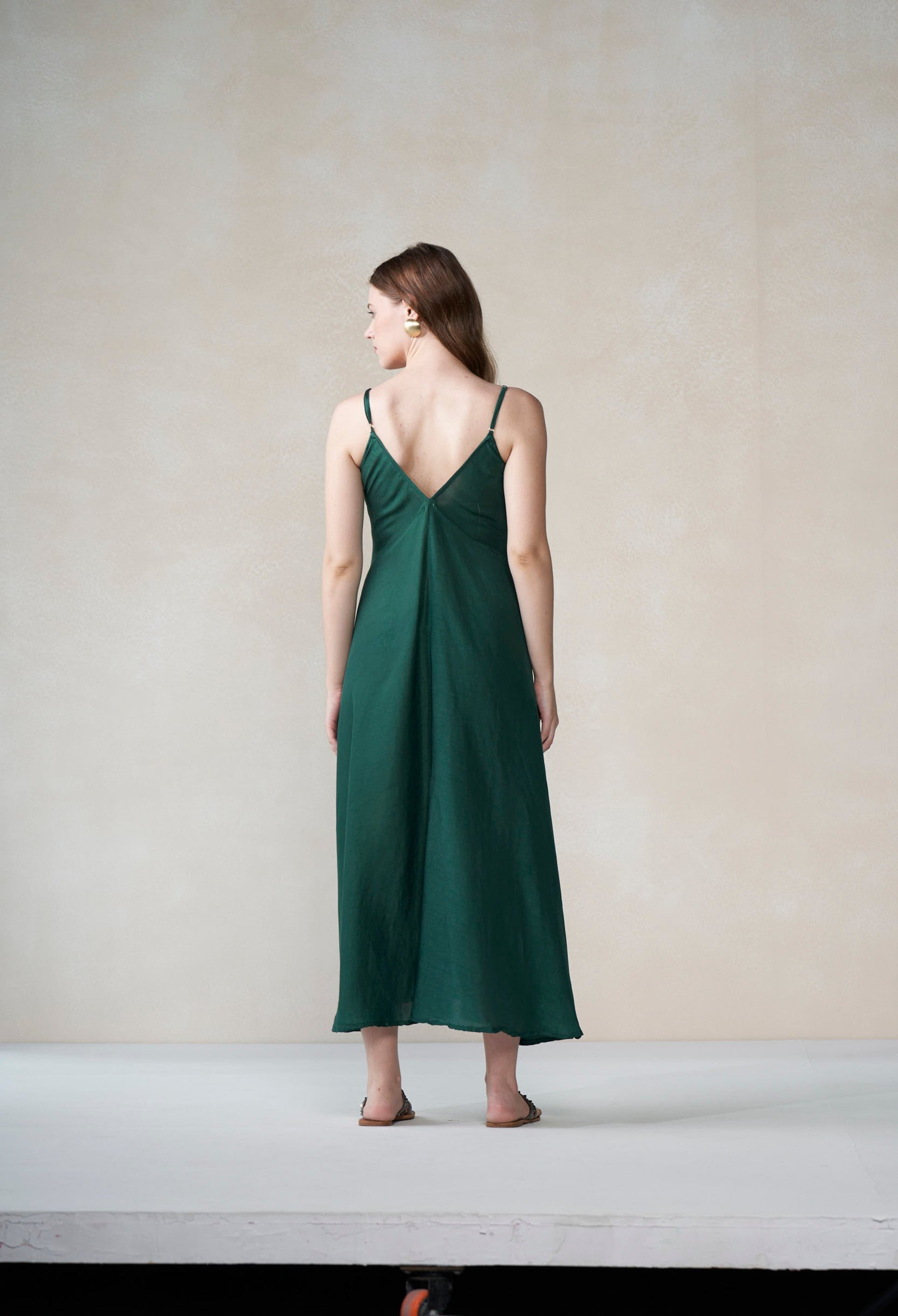 Woman wearing a green slip dress against a plain background