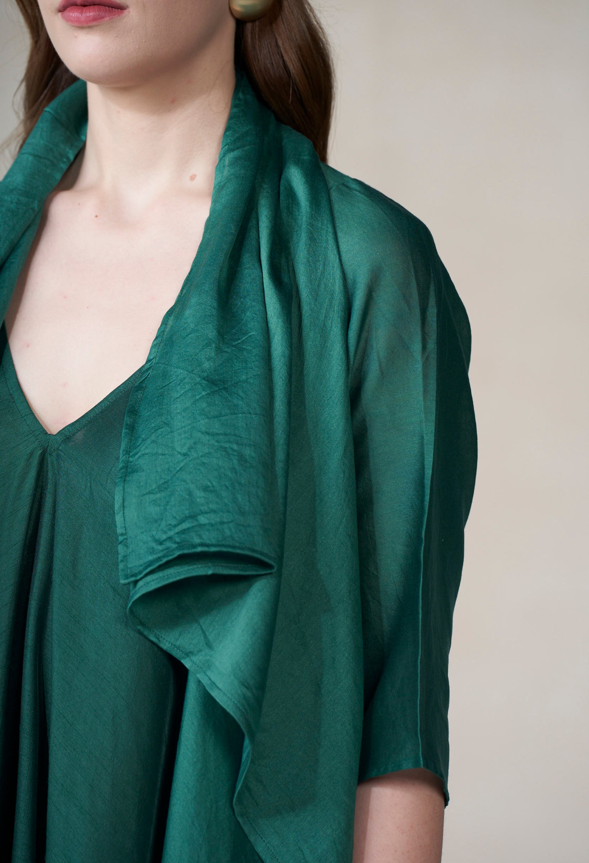 Green scarf draped over a person's shoulders against a neutral background