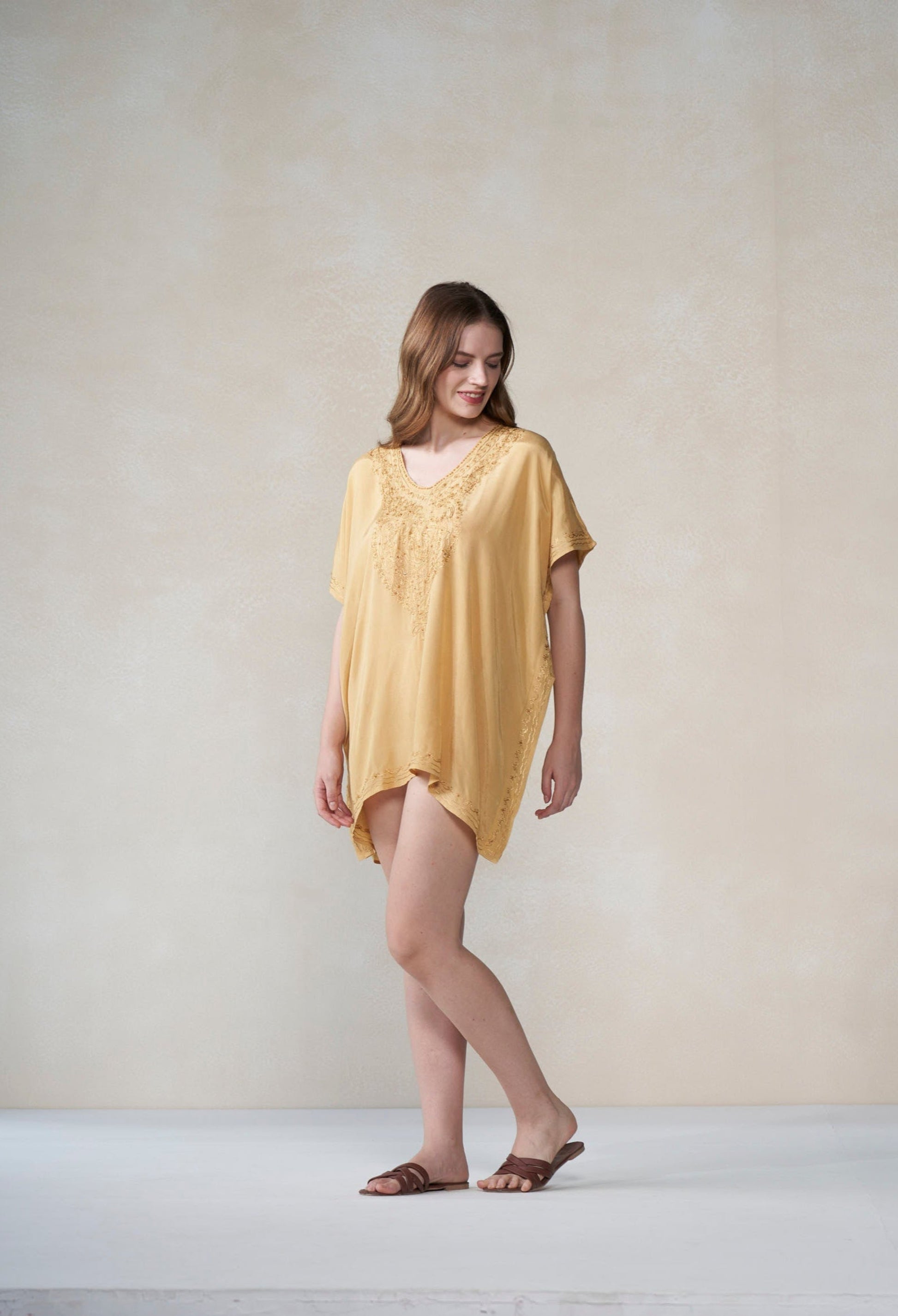 Woman wearing a yellow kaftan against a plain background