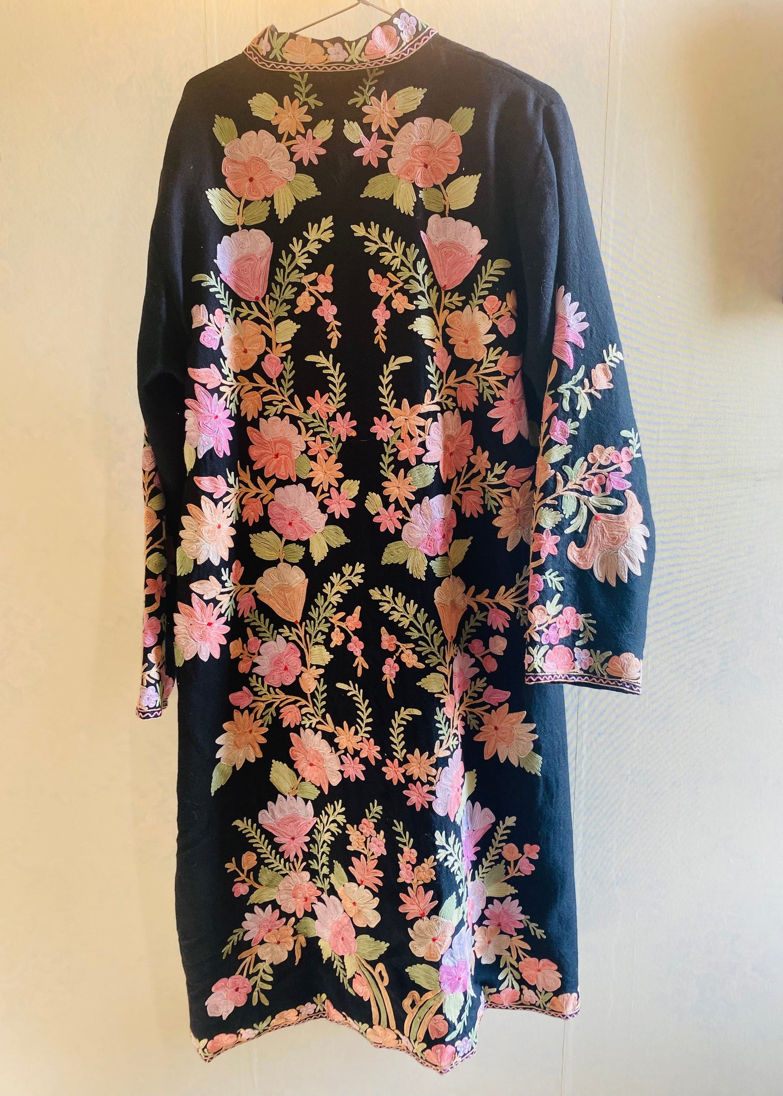 Floral patterned dress on a hanger against a plain background