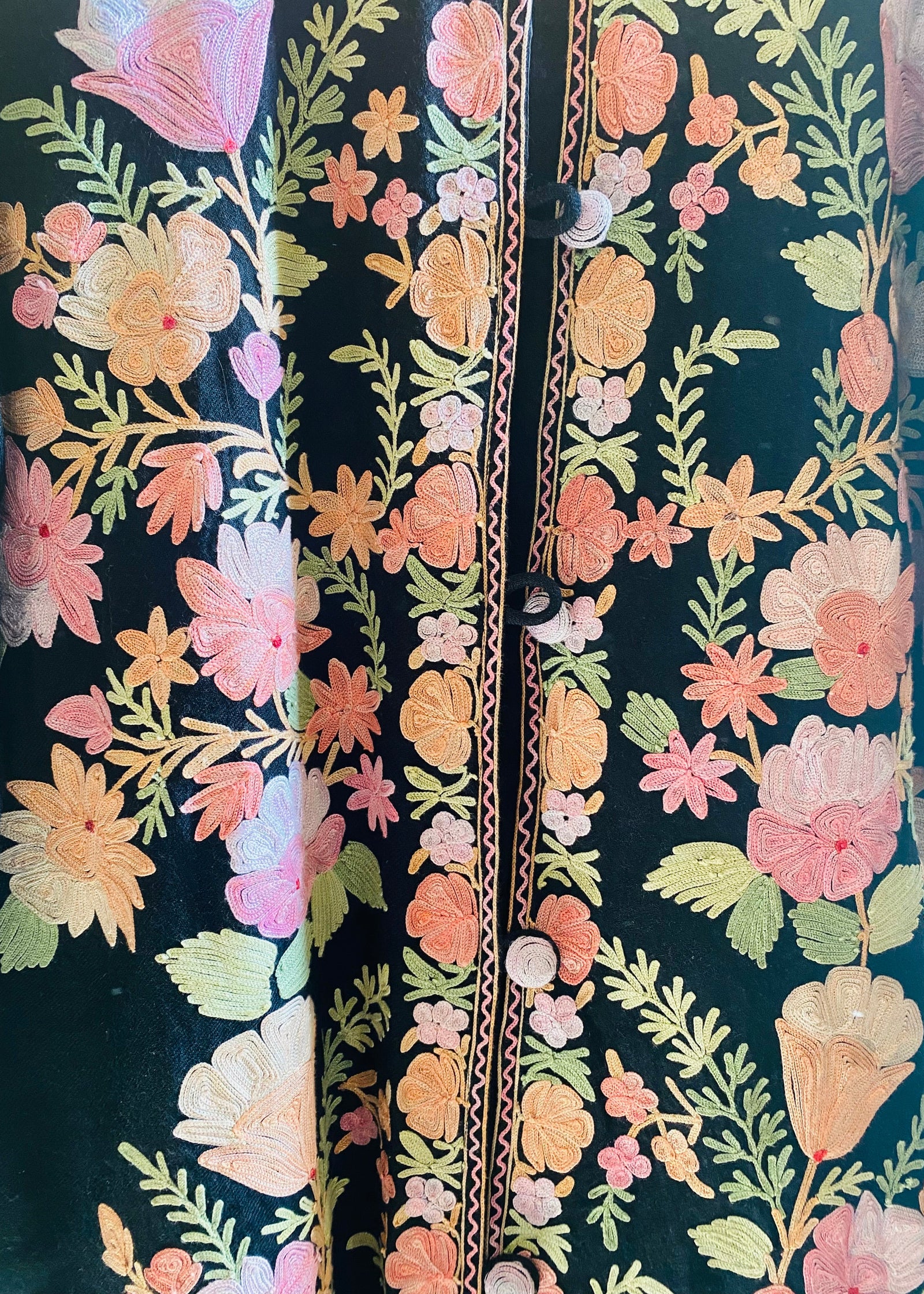 Floral kashmiri hand embroidery on a dark fabric background